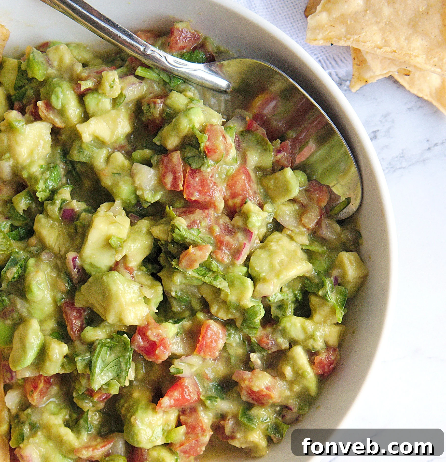 Homemade chunky guacamole in a bowl, garnished with a lime wedge and cilantro, ready to be enjoyed.