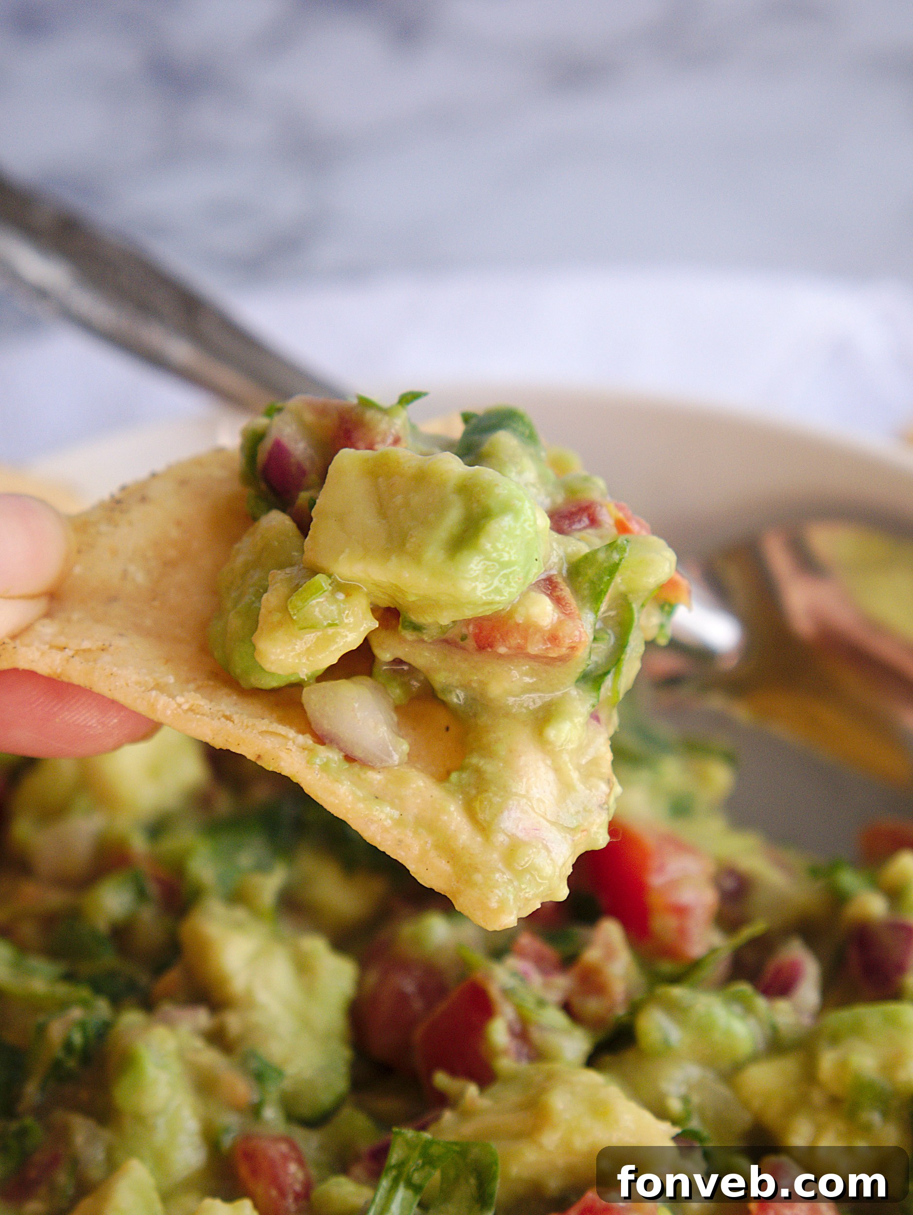 A bowl of fresh guacamole with all ingredients clearly visible in a vibrant setting.