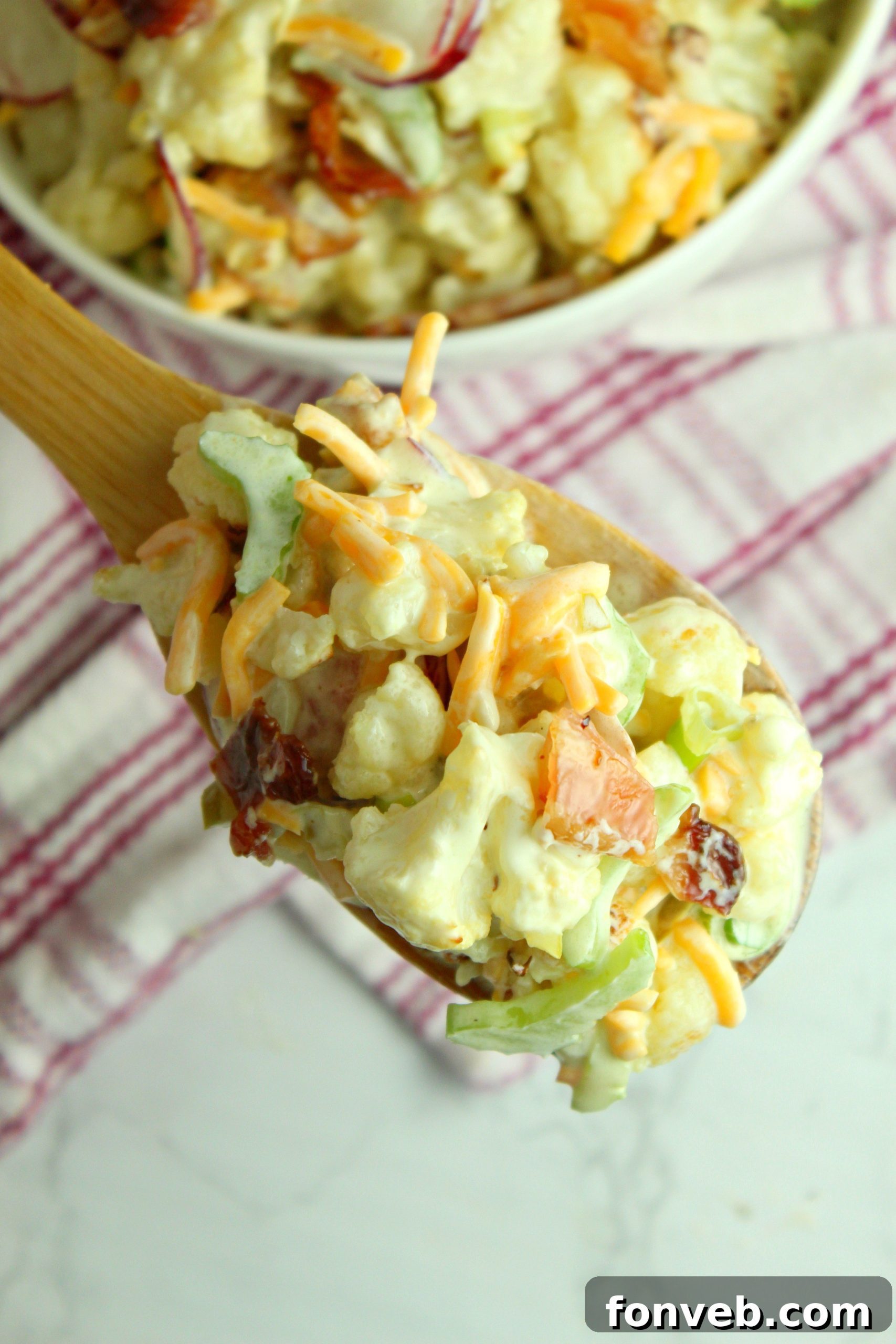 Large bowl of Loaded Cauliflower Salad with a serving spoon