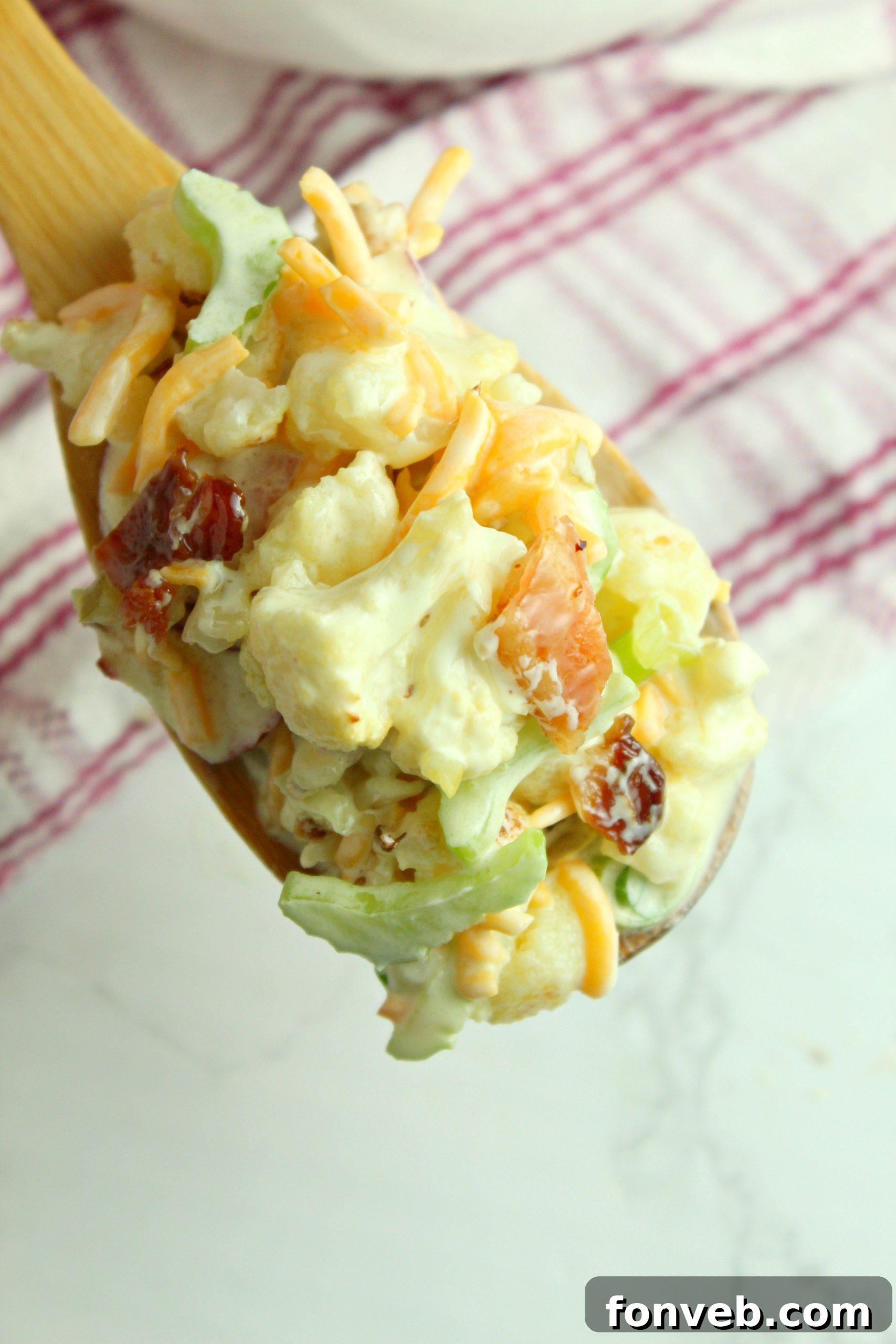 A serving of Loaded Cauliflower Salad on a plate next to grilled food