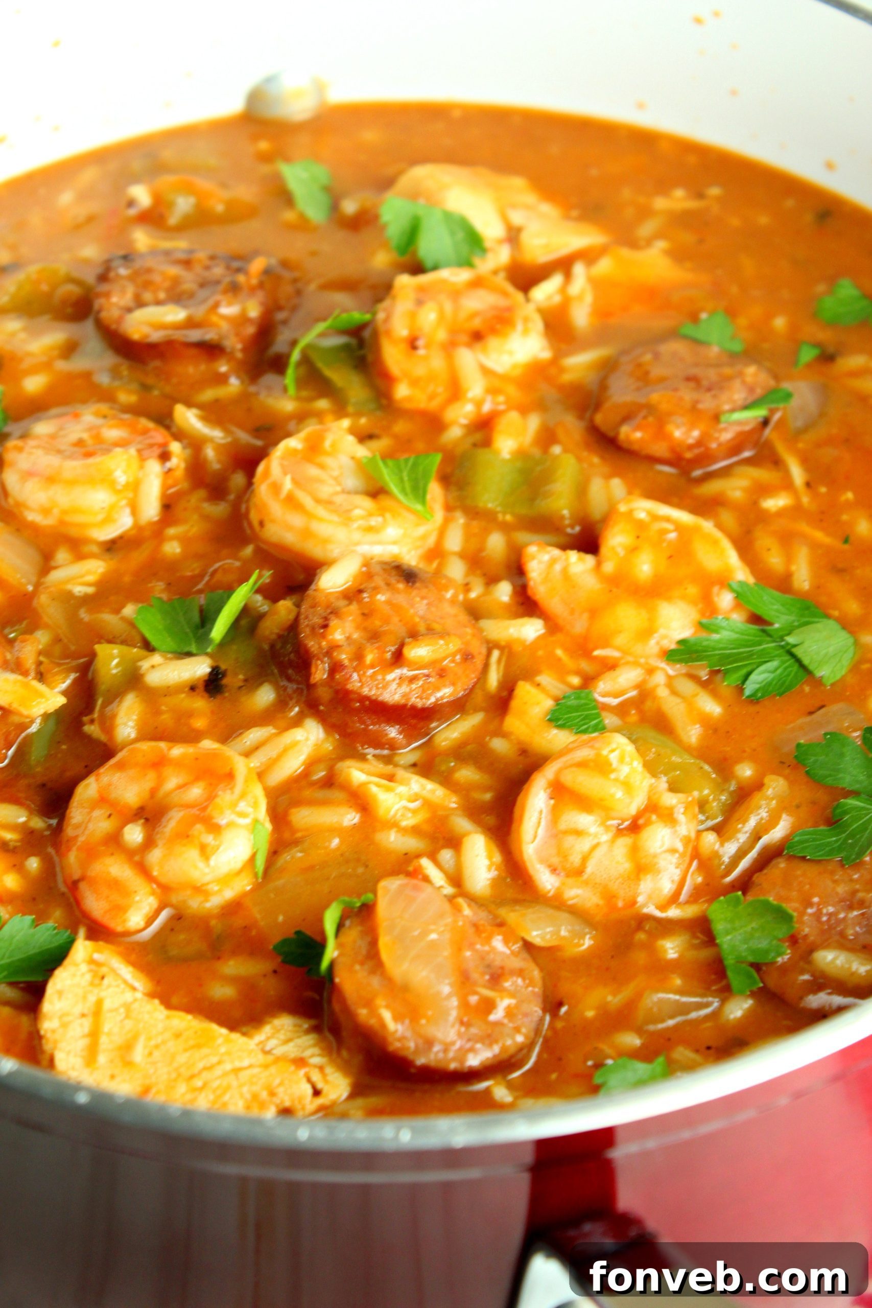 Spicy Cajun Jambalaya Soup 2 A vibrant bowl of Jambalaya Soup, garnished with fresh parsley, featuring visible pieces of sausage, shrimp, and vegetables in a rich, reddish broth.