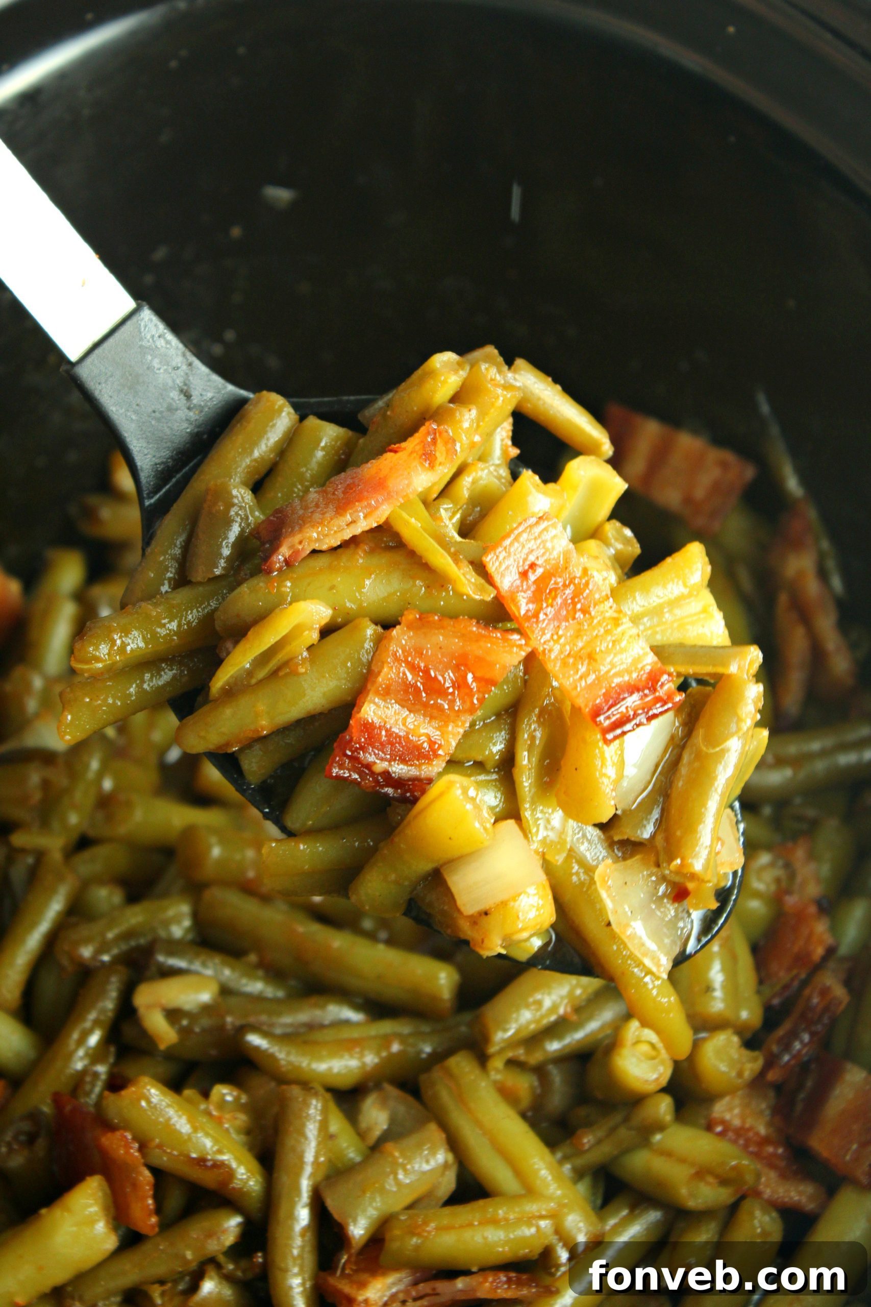 A large ceramic pot filled with Slow Cooker Buttery Bacon Green Beans, steaming gently, ready for serving.