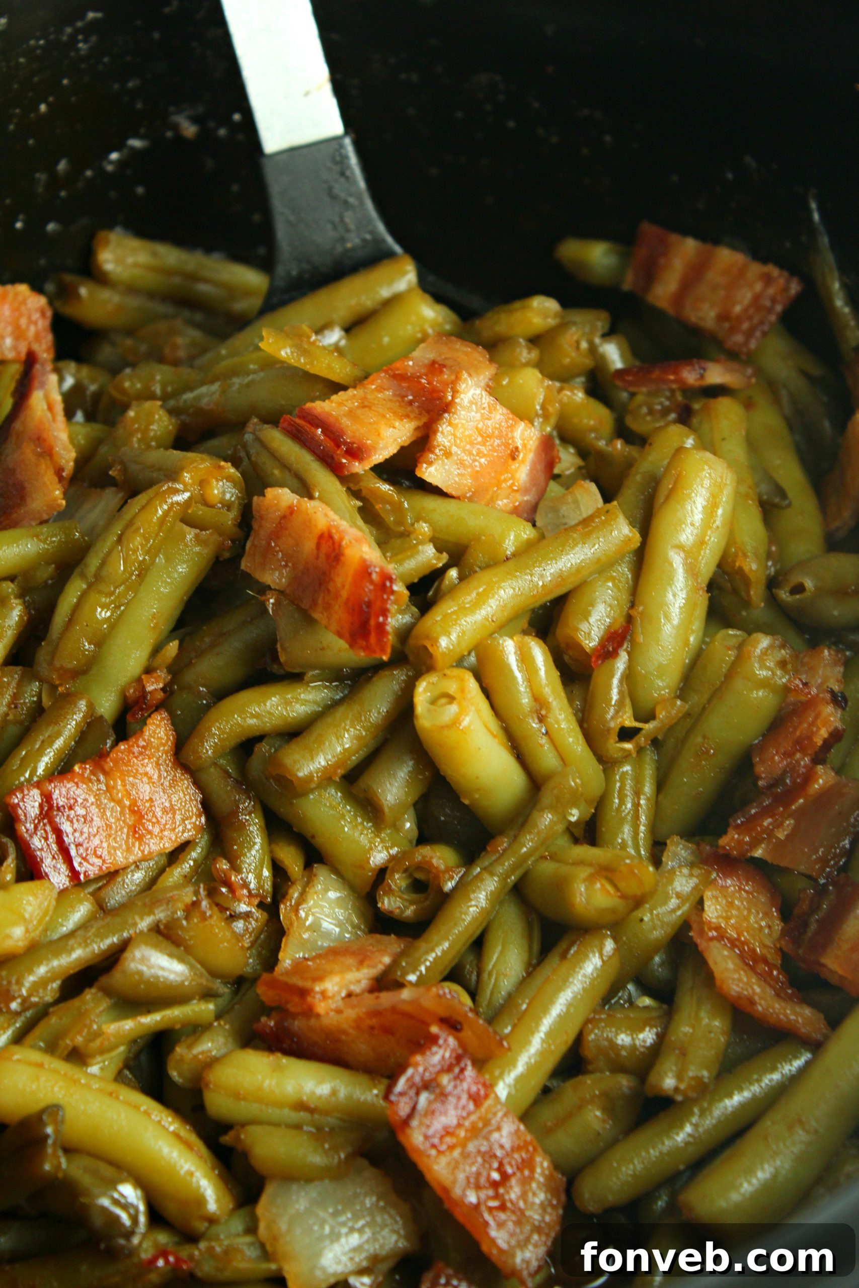 A serving of Slow Cooker Buttery Bacon Green Beans presented alongside other rustic meal elements, suggesting it as part of a hearty dinner.