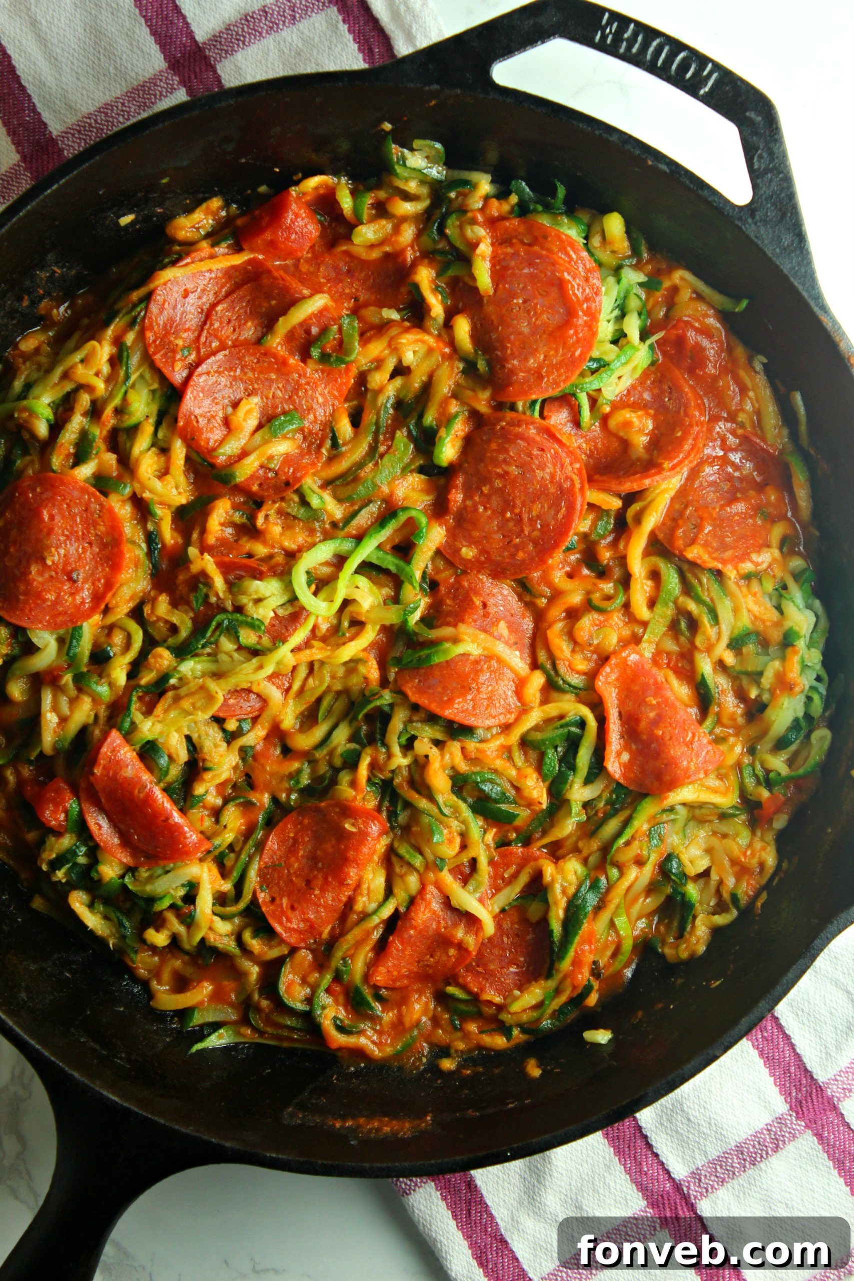 Cooked zucchini noodles with rich tomato sauce and savory pepperoni slices