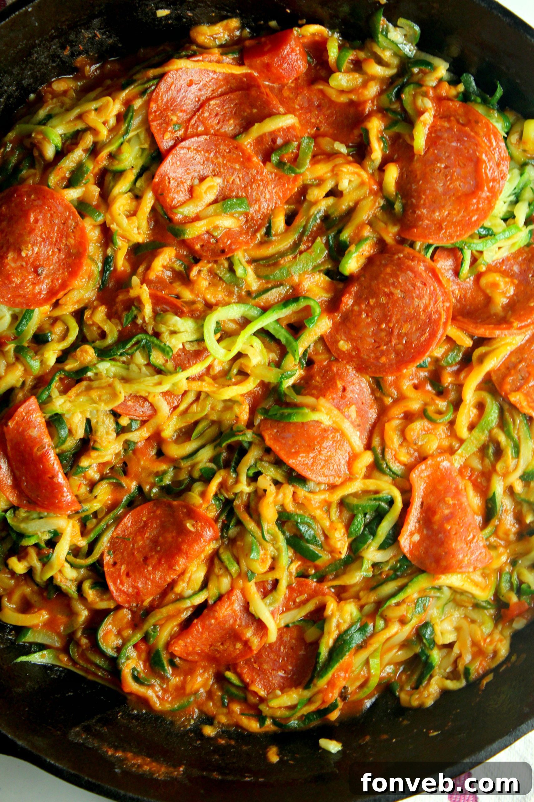 Preparing zucchini noodles in a large skillet with aromatic ingredients