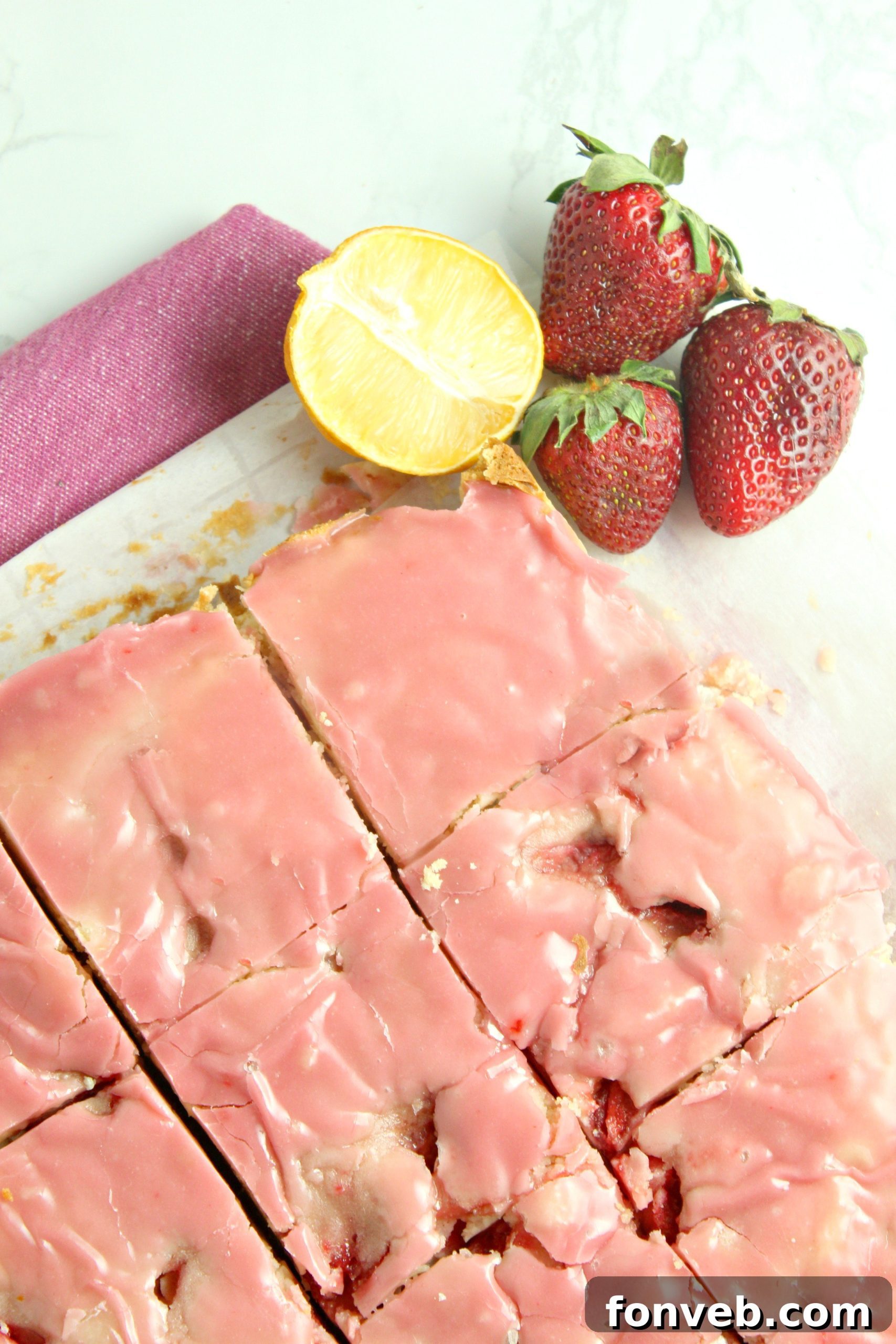 Stacked strawberry lemon blondies showing their thick, chewy texture and the generous pink icing on top.
