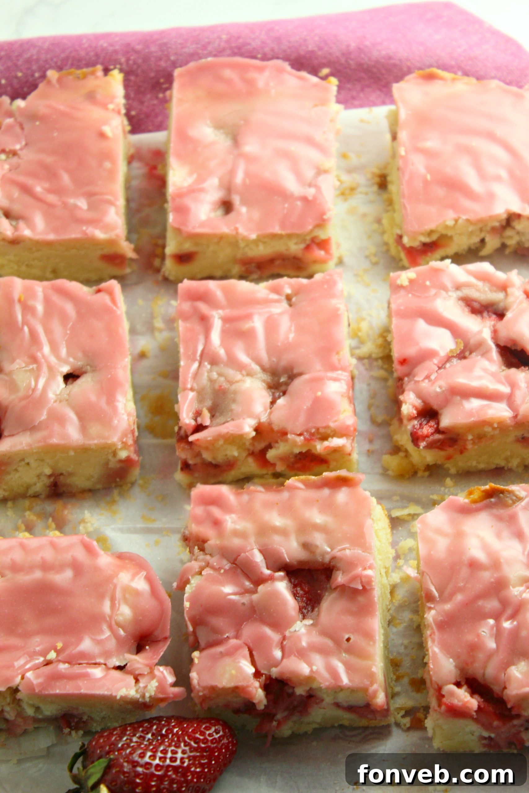A close-up of a single strawberry lemon blondie slice, showcasing the thick, sweet icing drizzled over the top.