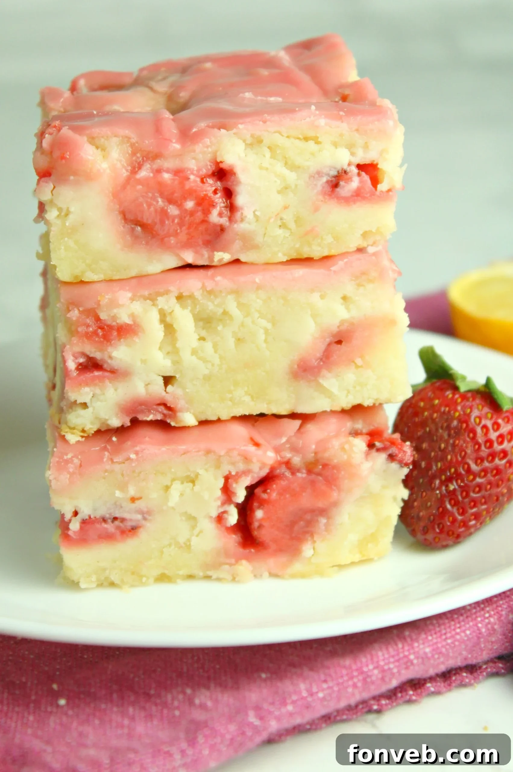 A tray of freshly baked strawberry lemon blondies, glistening with icing, ready to be served.