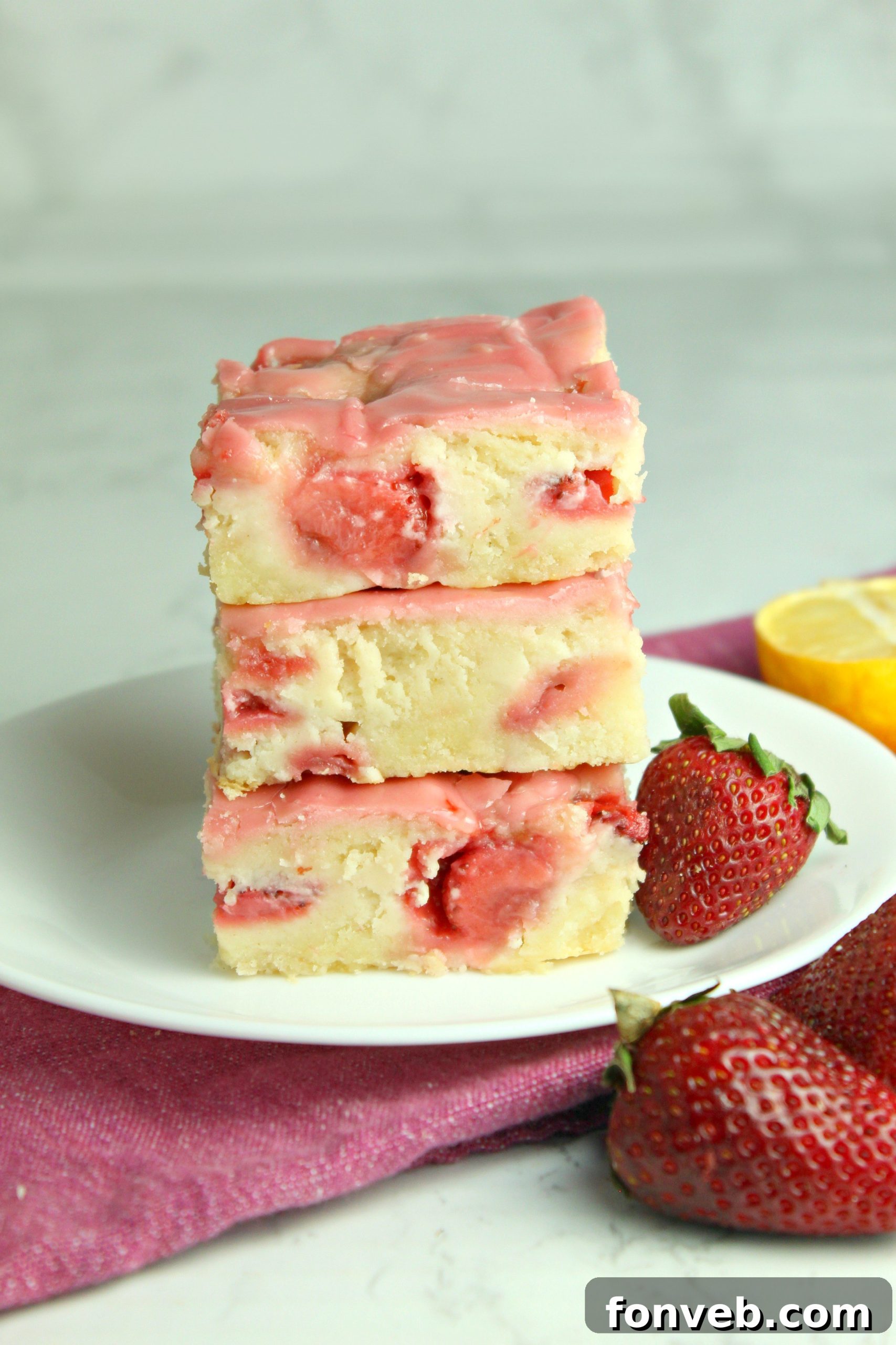 A stack of three blondies on a plate, with a fork ready to take a bite, highlighting the delicious texture.