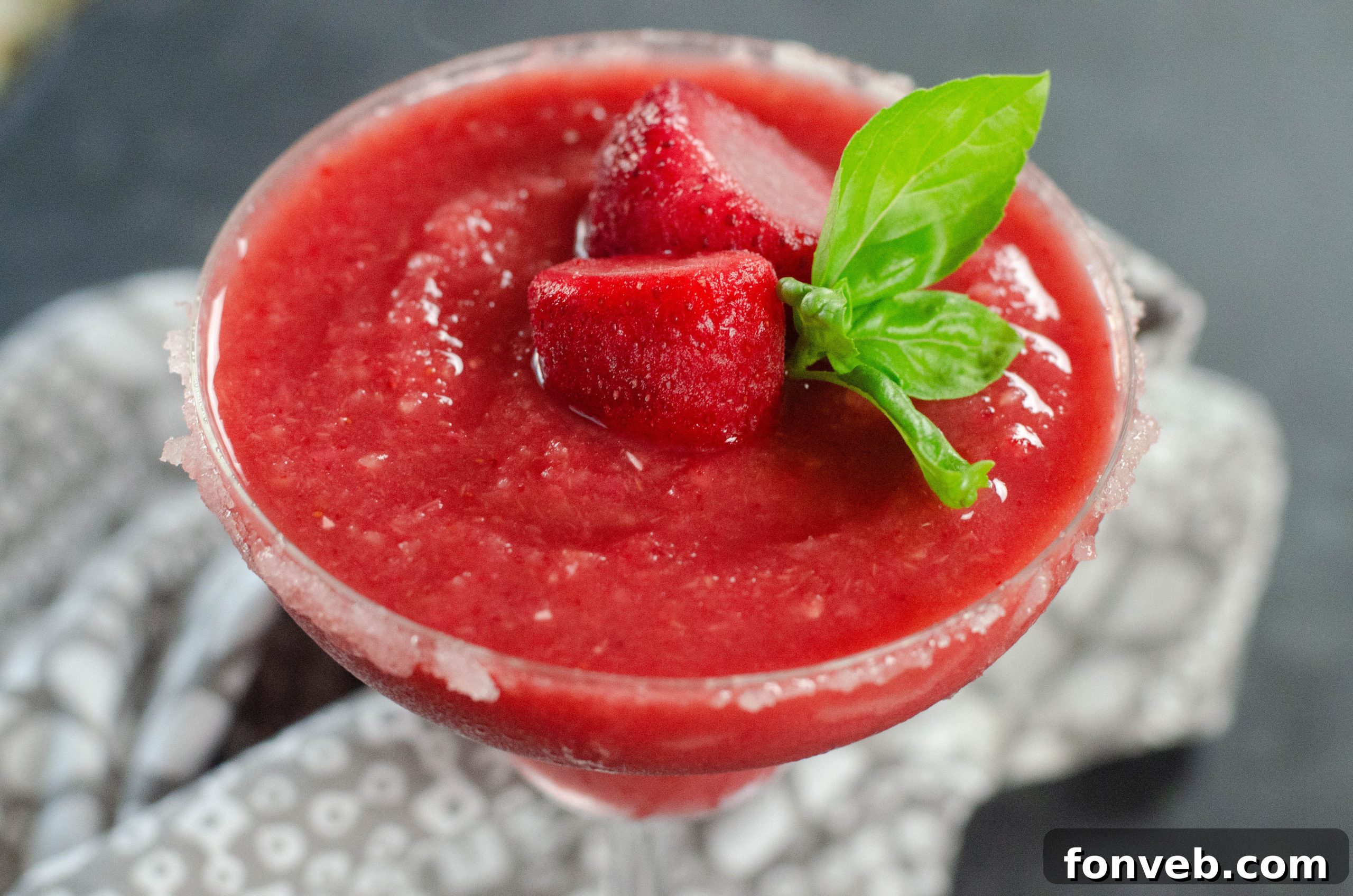 Frozen Strawberry Dream 3 Two glasses of Strawberry Daiquiri with a bowl of fresh strawberries beside them.