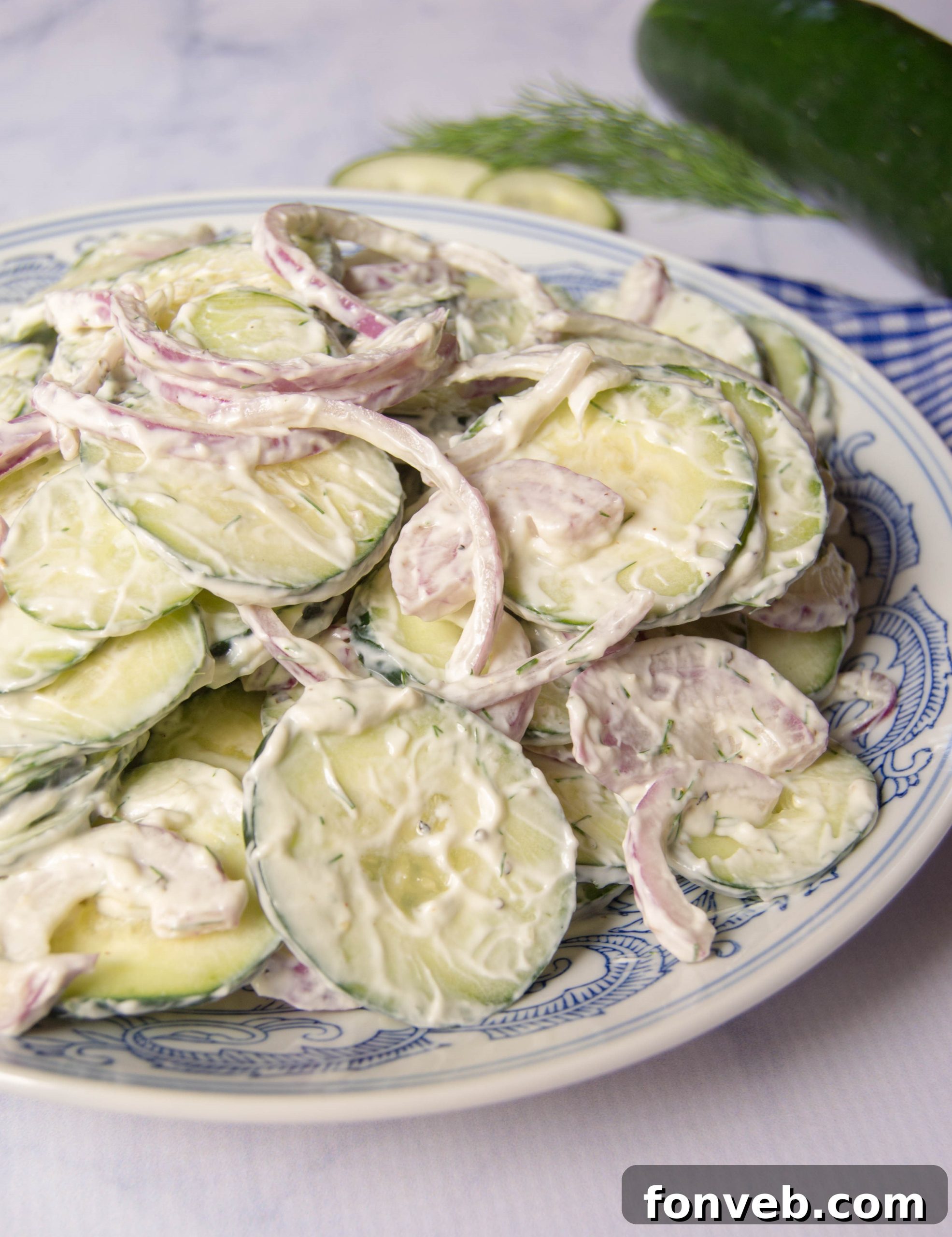 A vibrant bowl of classic creamy cucumber salad, garnished with fresh dill, ready to be served at a summer gathering.
