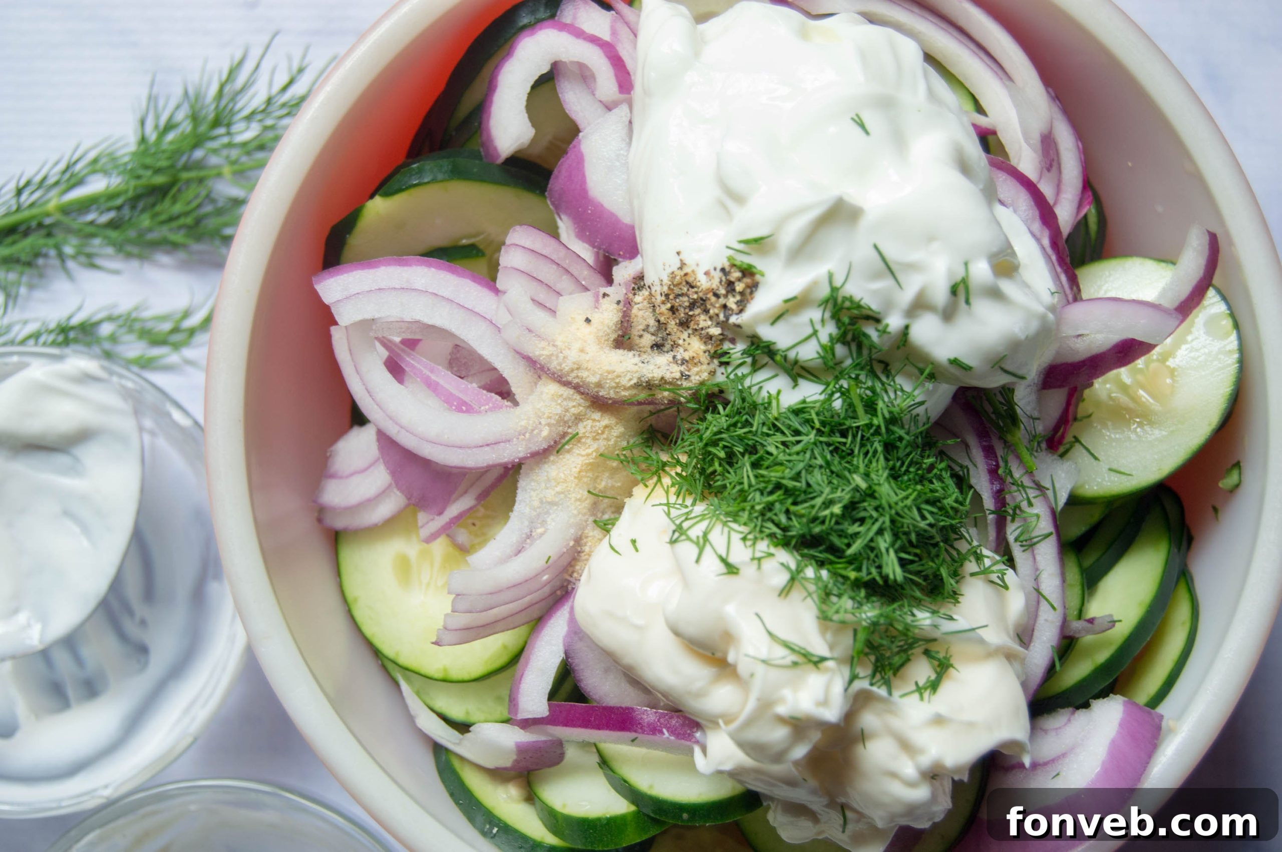 Freshly sliced cucumbers being prepared for the creamy salad, showcasing the crispness of the vegetable.