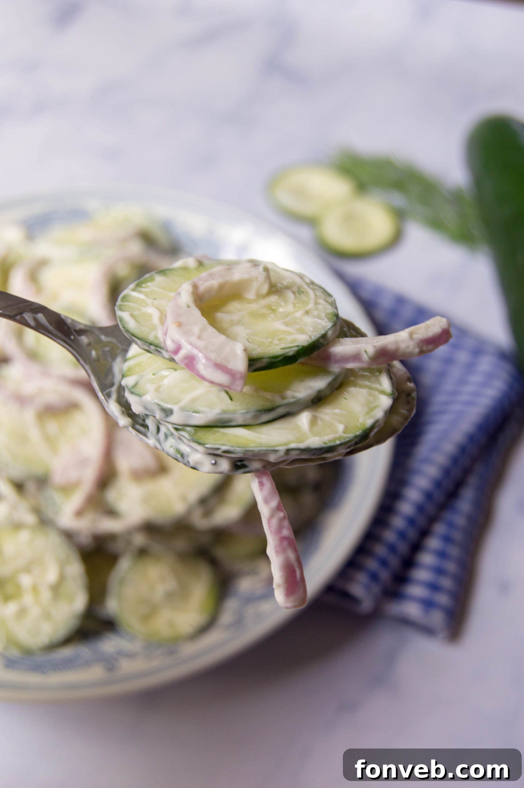 Close-up of the creamy cucumber salad with visible specks of fresh dill, emphasizing its fresh ingredients.