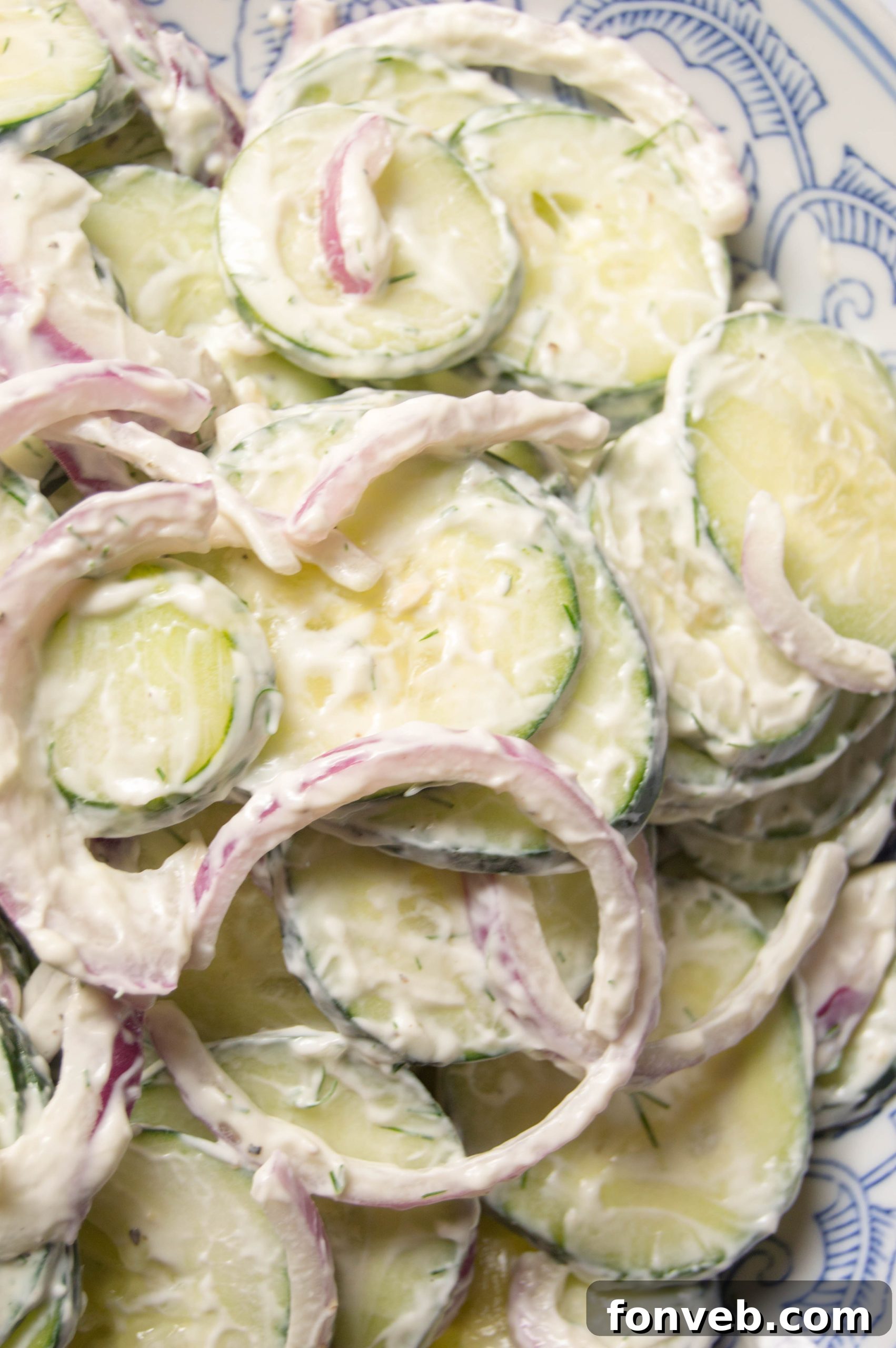 Overhead view of a prepared bowl of creamy cucumber salad, highlighting its freshness and inviting appearance.