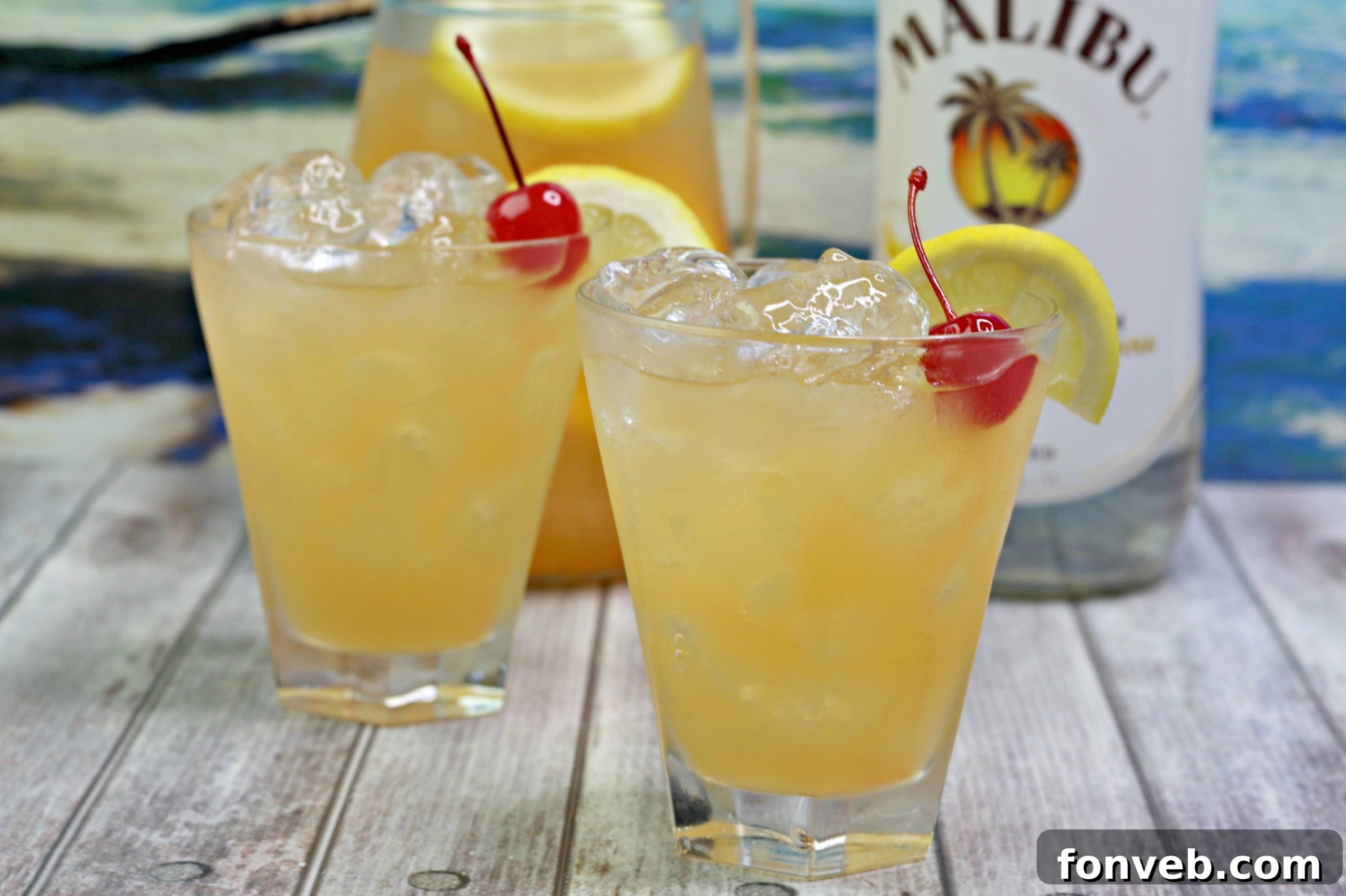 Close-up of a glass of banana rum punch with ice and fruit garnishes