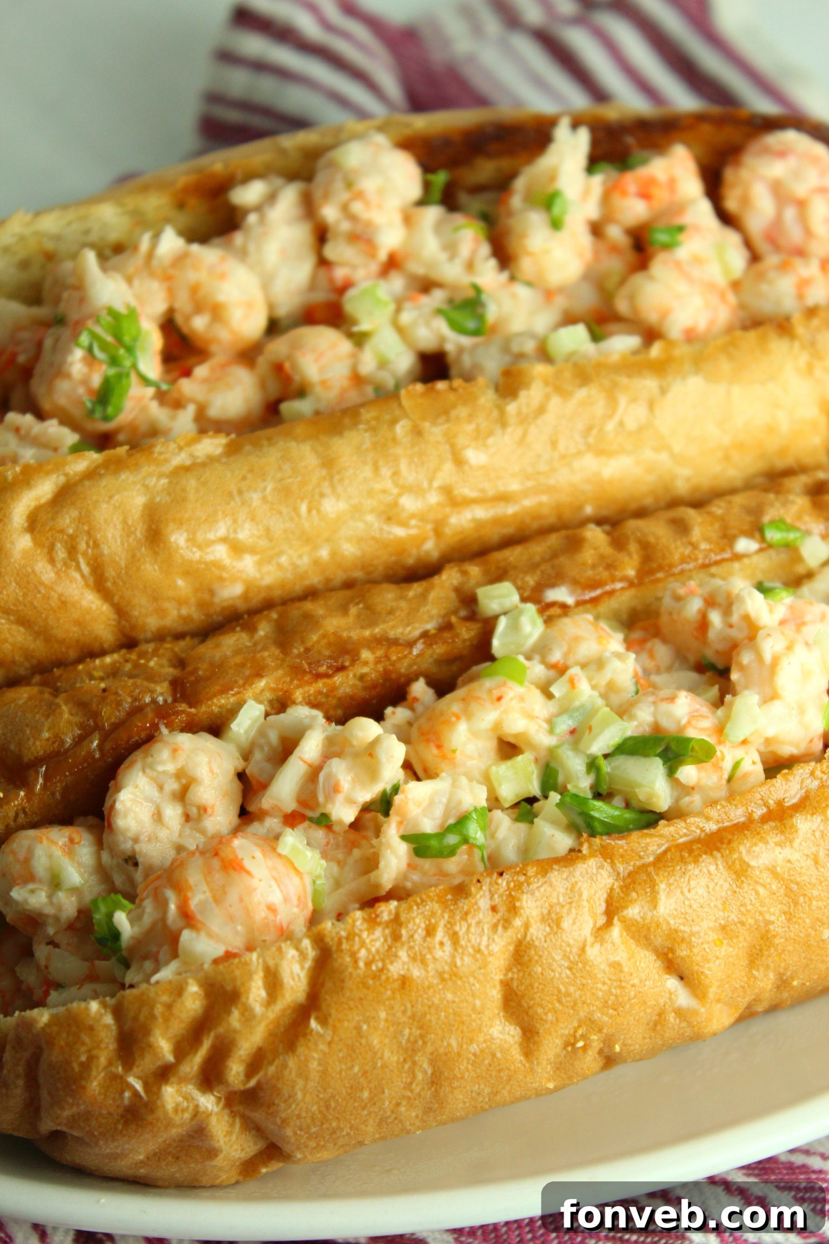 Lobster roll filling being scooped into a toasted bun