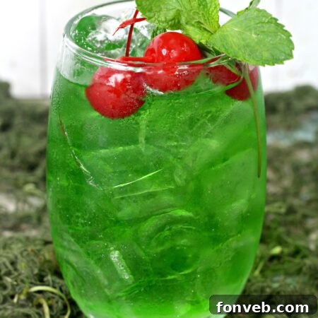 A glass of Liquid Marijuana Cocktail with lime and apple garnishes.