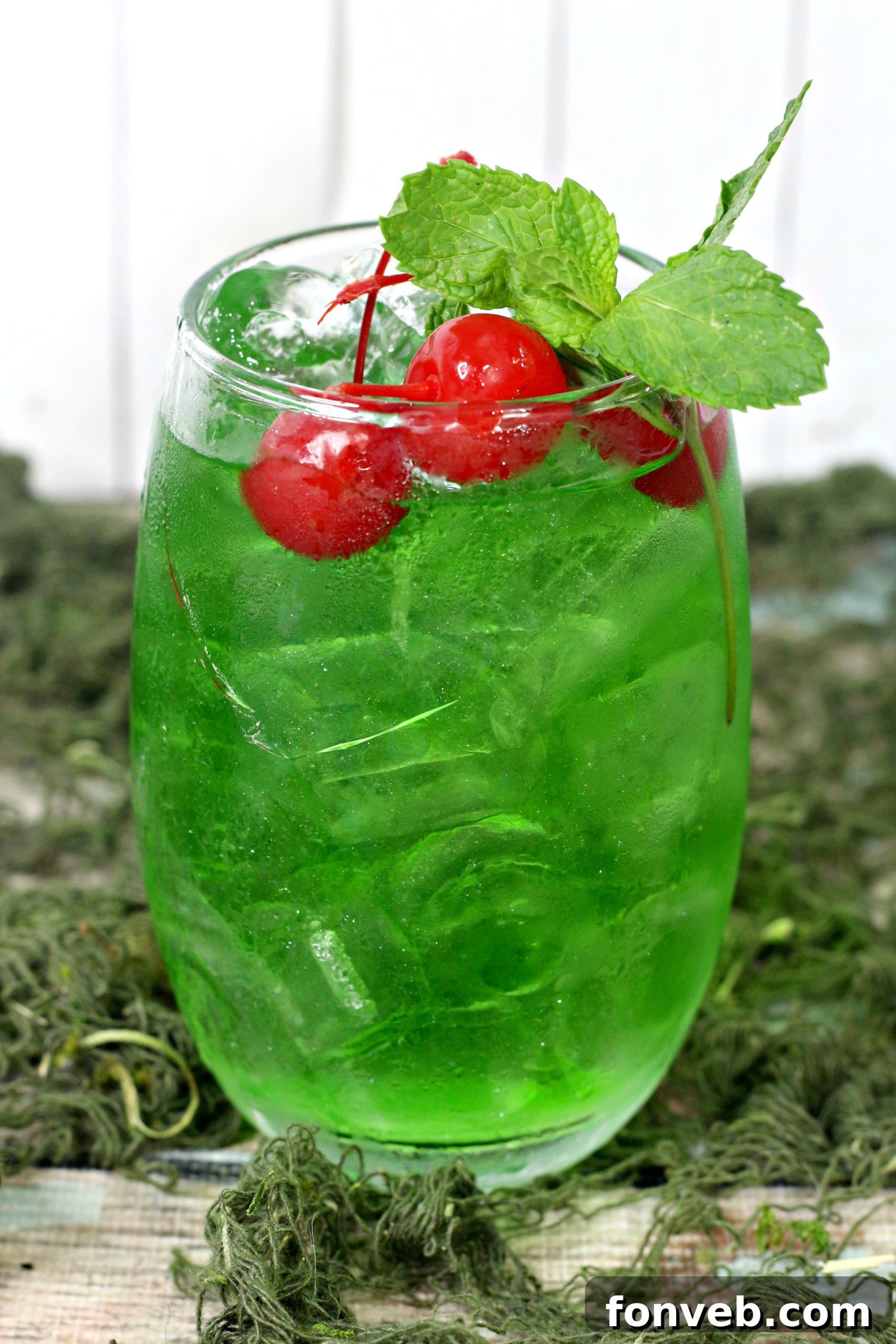 A close-up of a hand holding a Liquid Marijuana Cocktail against a blurred background.