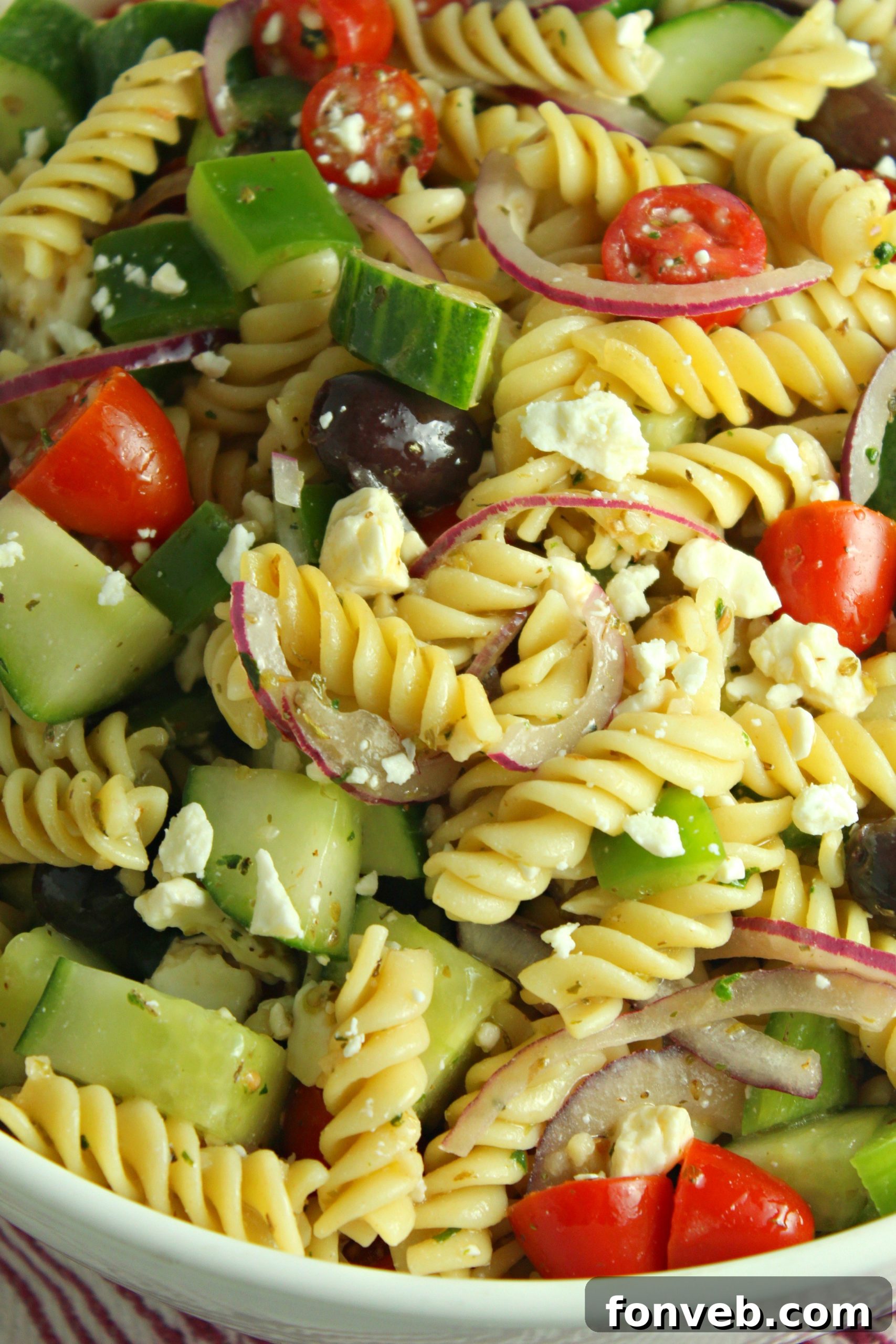Close-up of mixed Greek Pasta Salad in a serving bowl, ready to be enjoyed at a gathering.