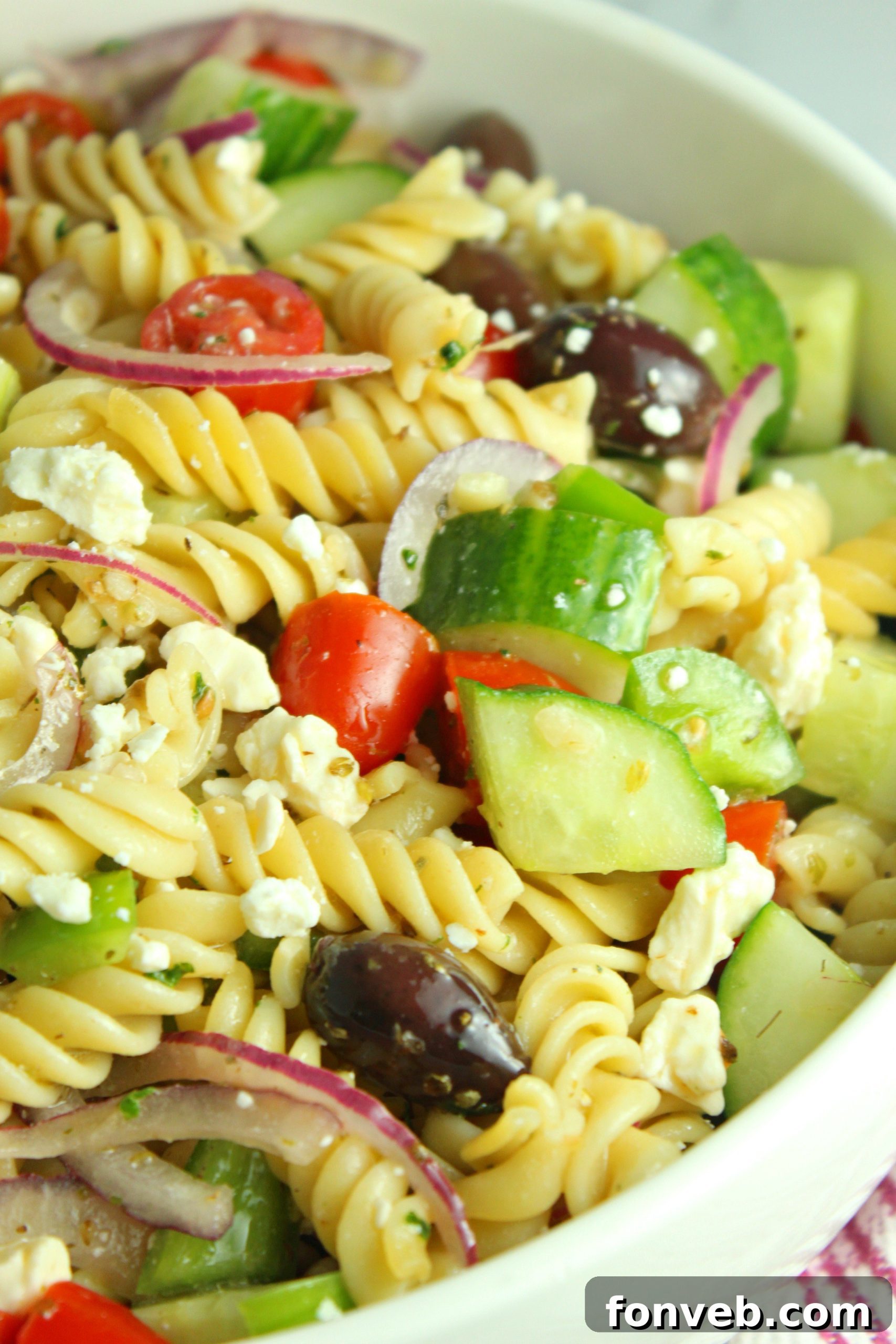 Overhead shot of a large white bowl filled with Greek Pasta Salad, emphasizing the generous portion.