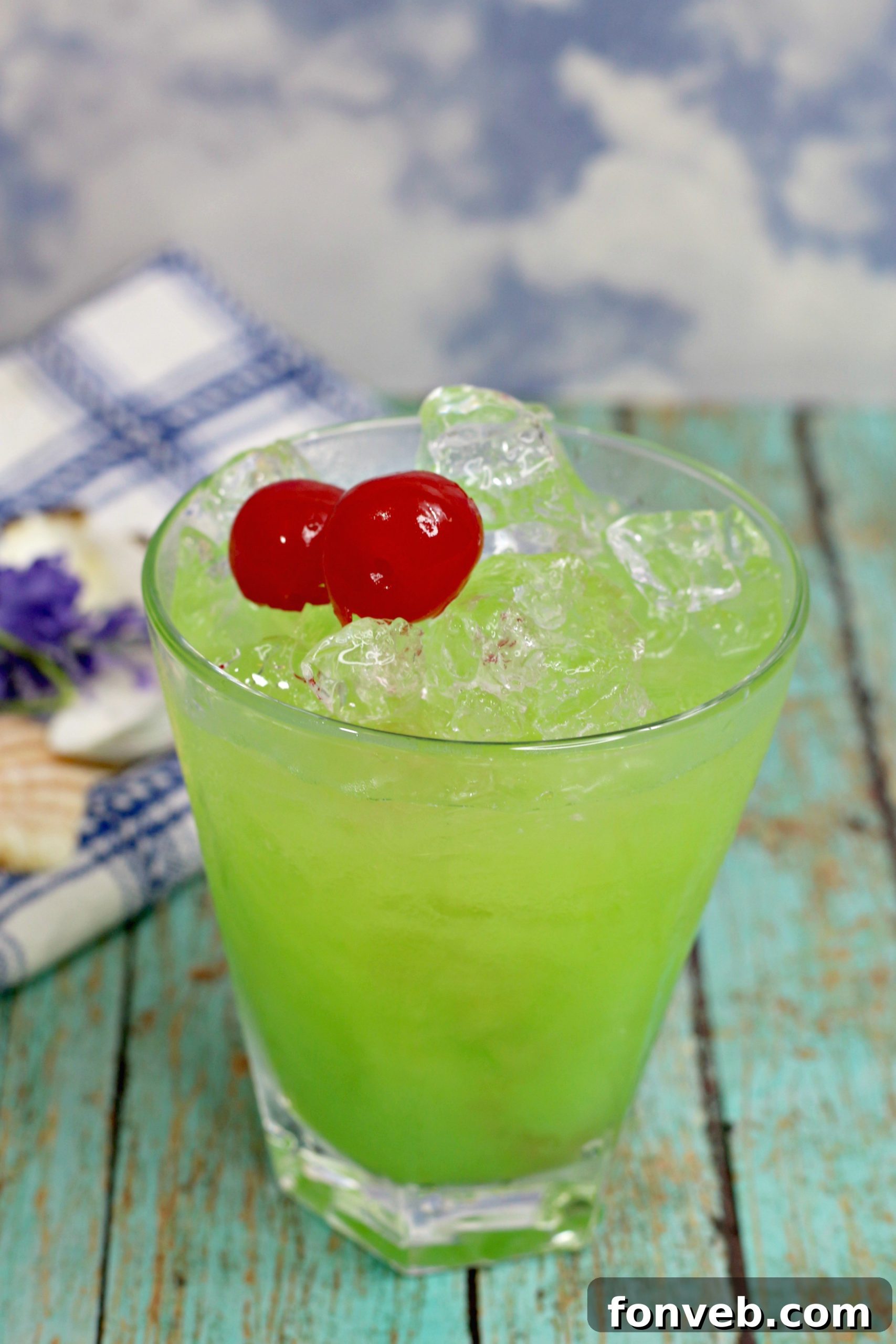 Two Green Iguana Cocktails garnished with orange slices, ready for a summer celebration.