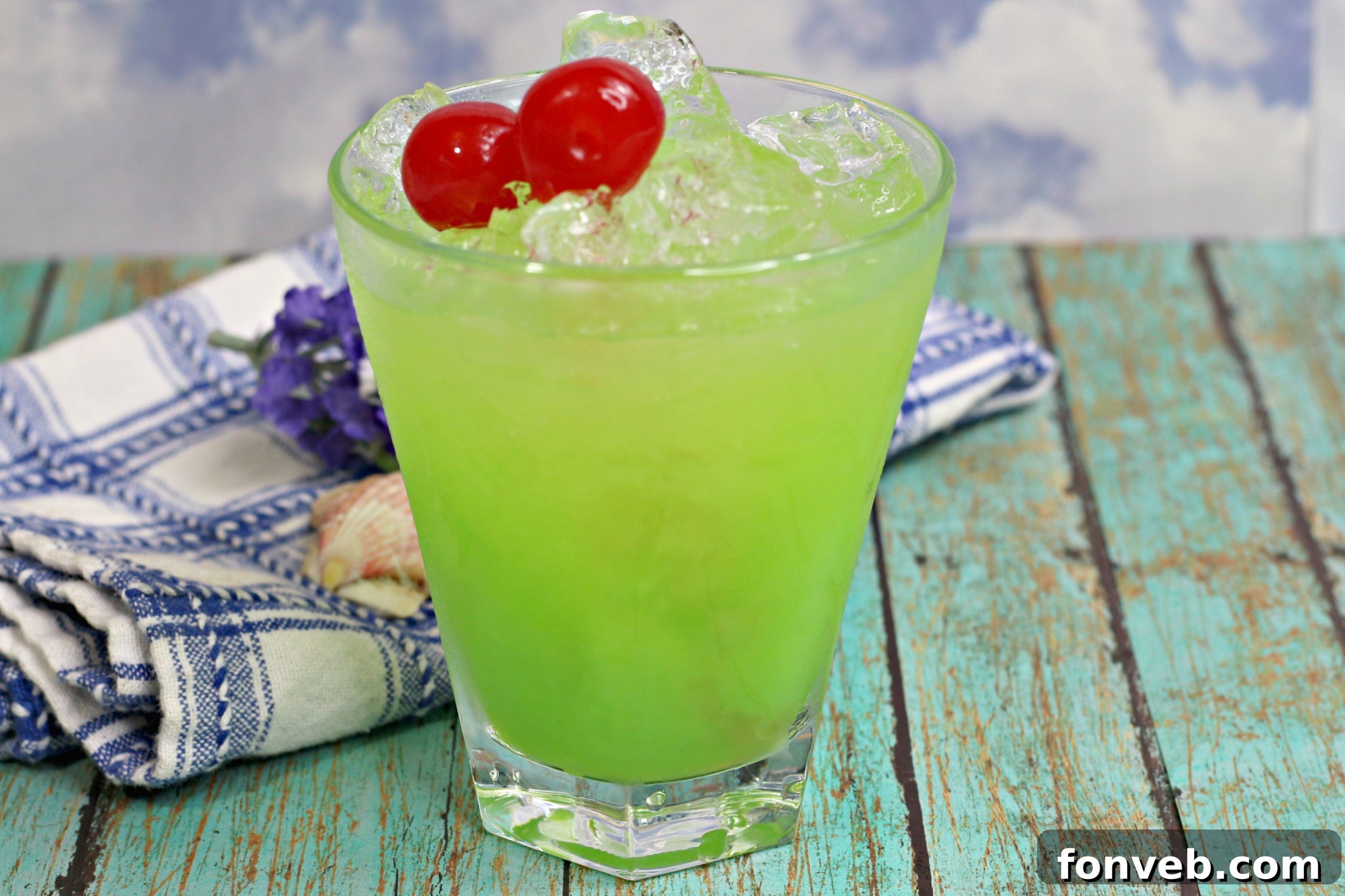 The Green Iguana Cocktail ready to be enjoyed, garnished with a lime and cherry.