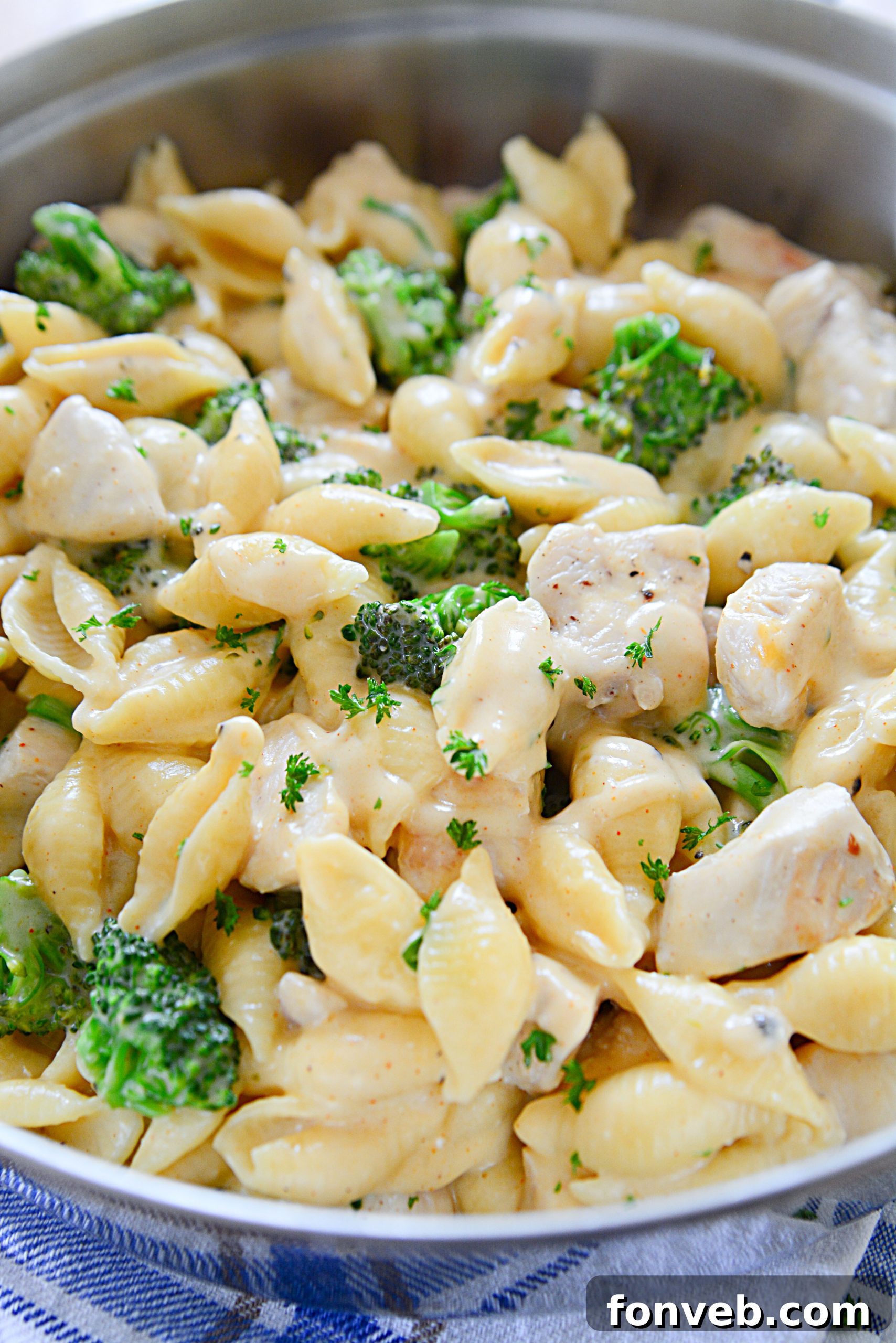Creamy Cheesy Chicken and Broccoli Shells 2 A close-up shot of Cheesy Chicken & Broccoli Shells in a white bowl, garnished with fresh parsley.