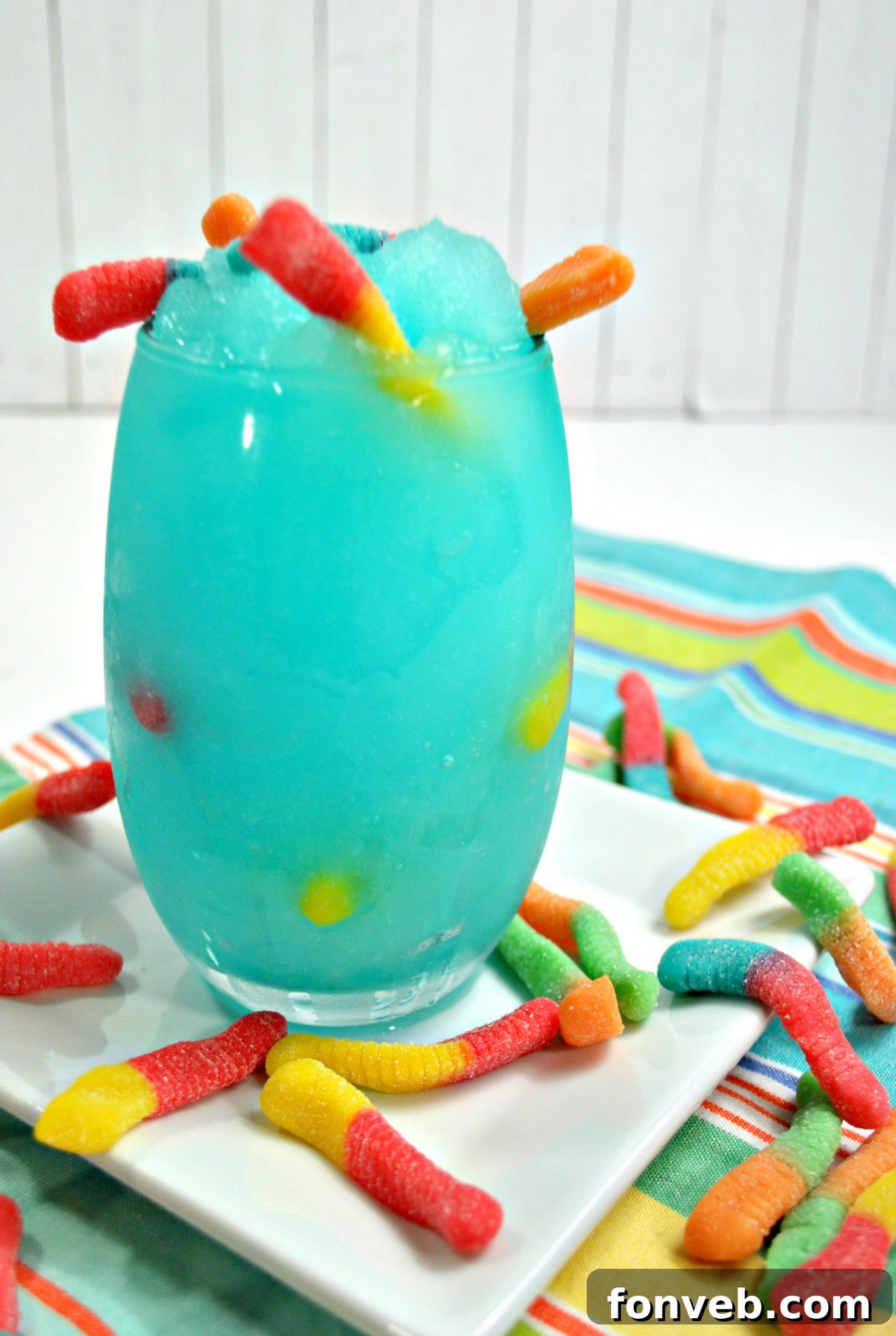 A close-up shot of the Drunken Sour Gummy Worm Cocktail, highlighting the slushy texture and the array of colorful gummy worms within the glass.