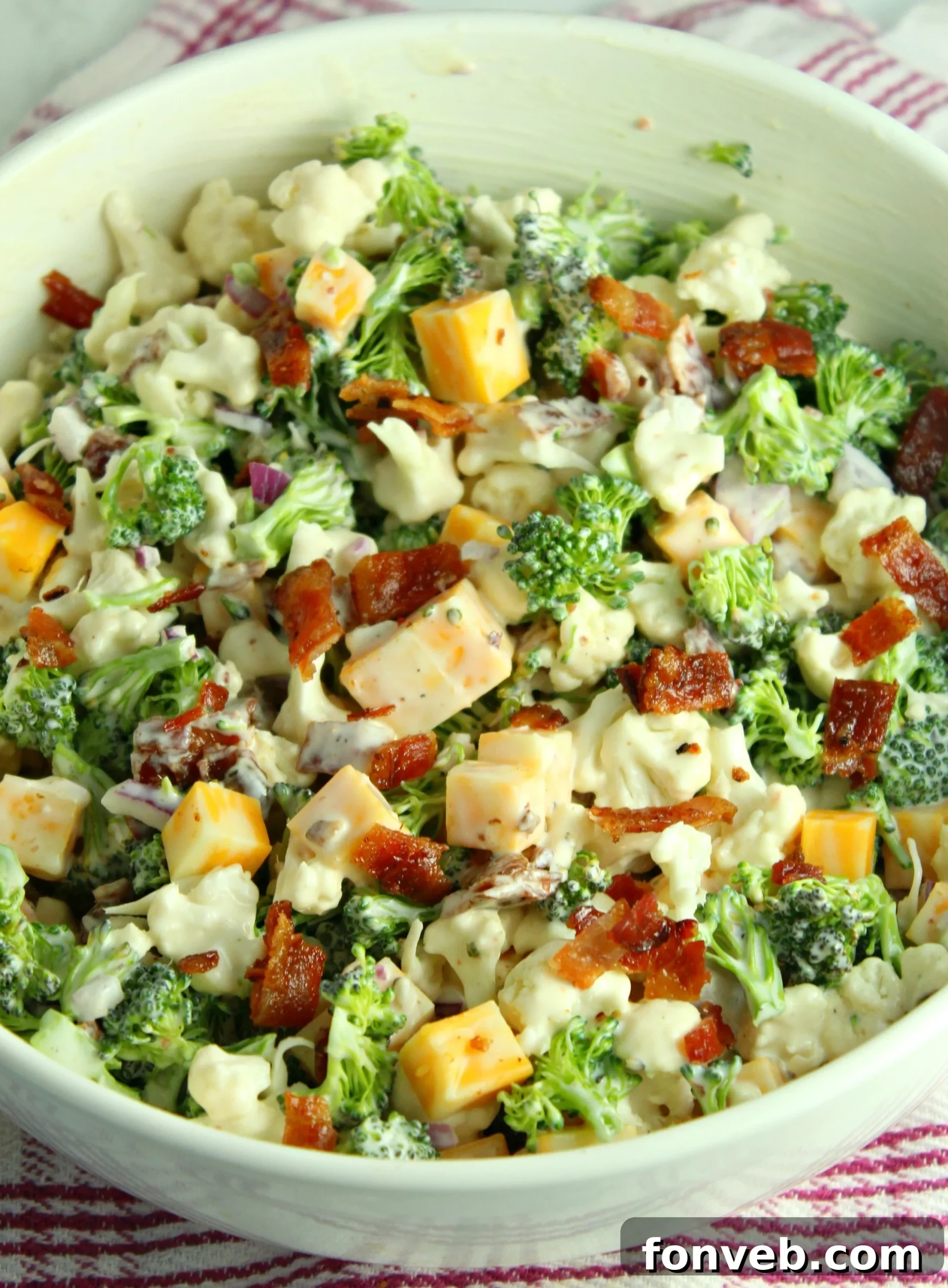 A serving of Loaded Broccoli Cauliflower Salad in a smaller white bowl.