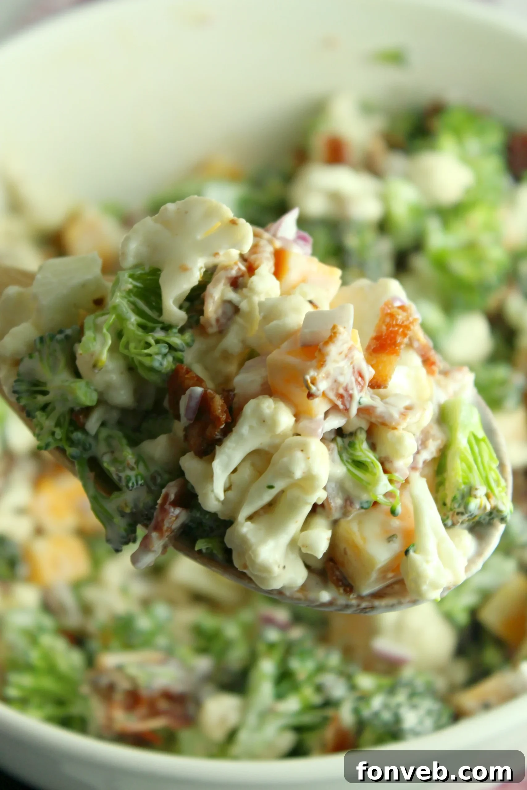 The dressing being poured over the mixed salad ingredients in a large bowl.