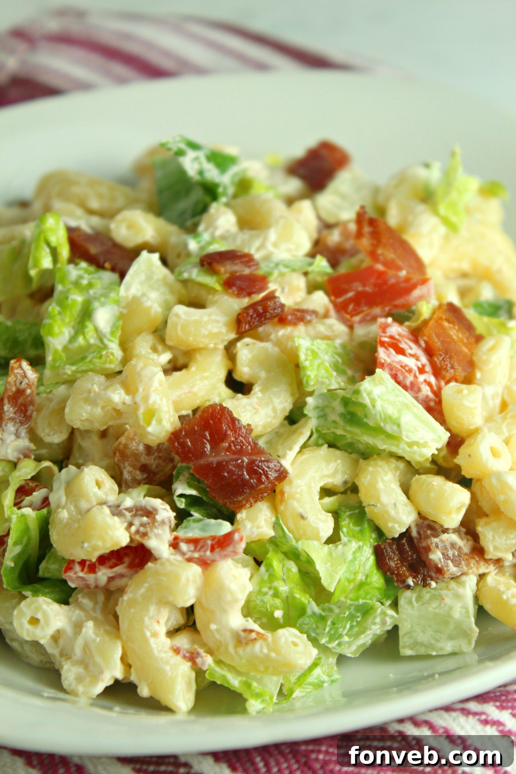 BLT Pasta Salad presented in a beautiful bowl on an outdoor table setting.