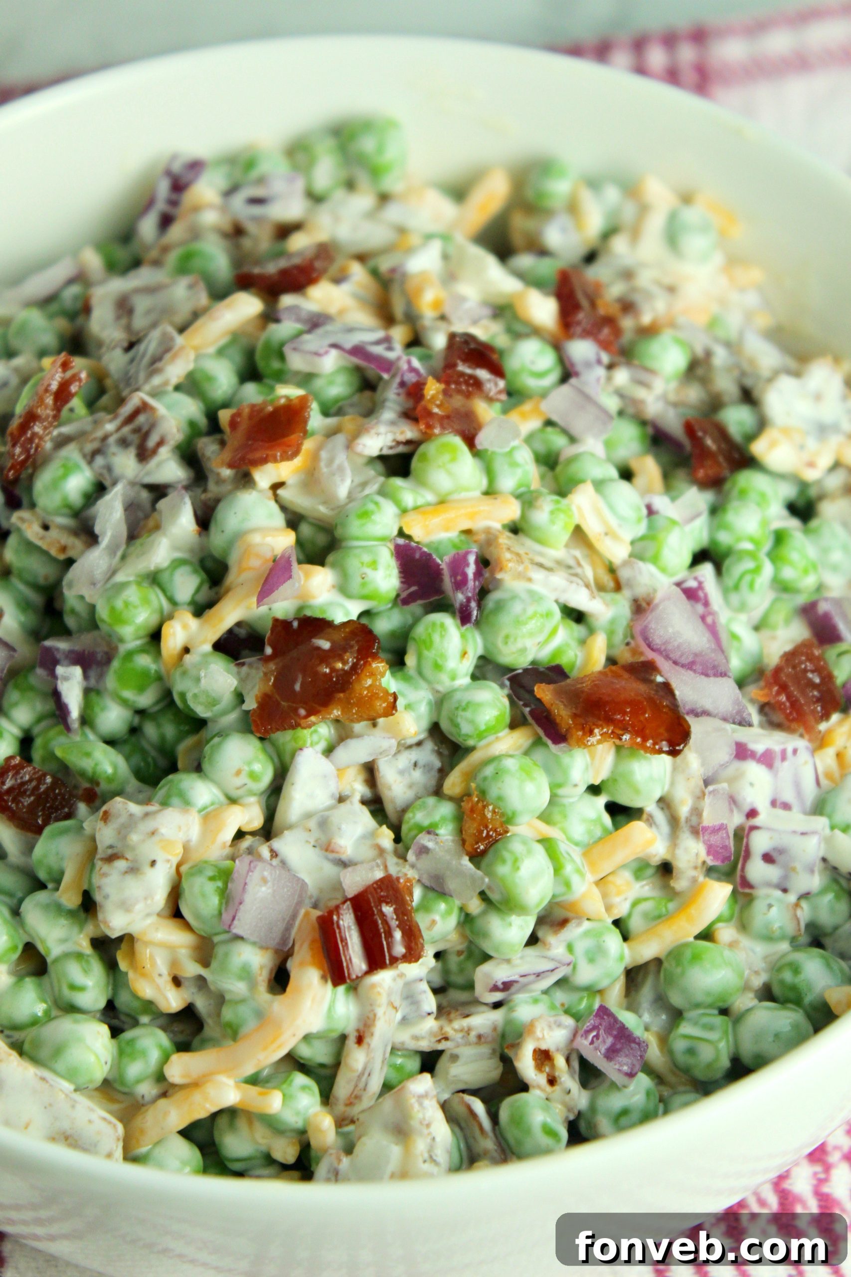Smoky Bacon and Sweet Pea Salad 2 A vibrant bowl of Creamy Bacon Pea Salad, showcasing crunchy peas, crispy bacon bits, and shredded cheddar cheese.