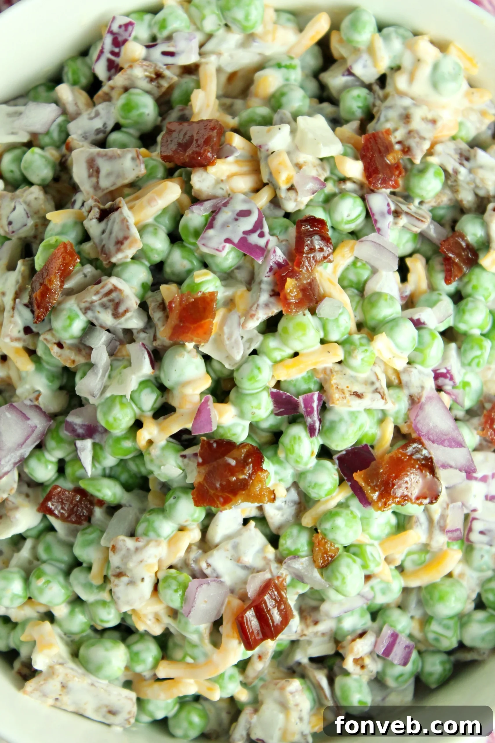 Smoky Bacon and Sweet Pea Salad 4 A serving of Creamy Bacon Pea Salad in a rustic bowl, garnished with fresh herbs.