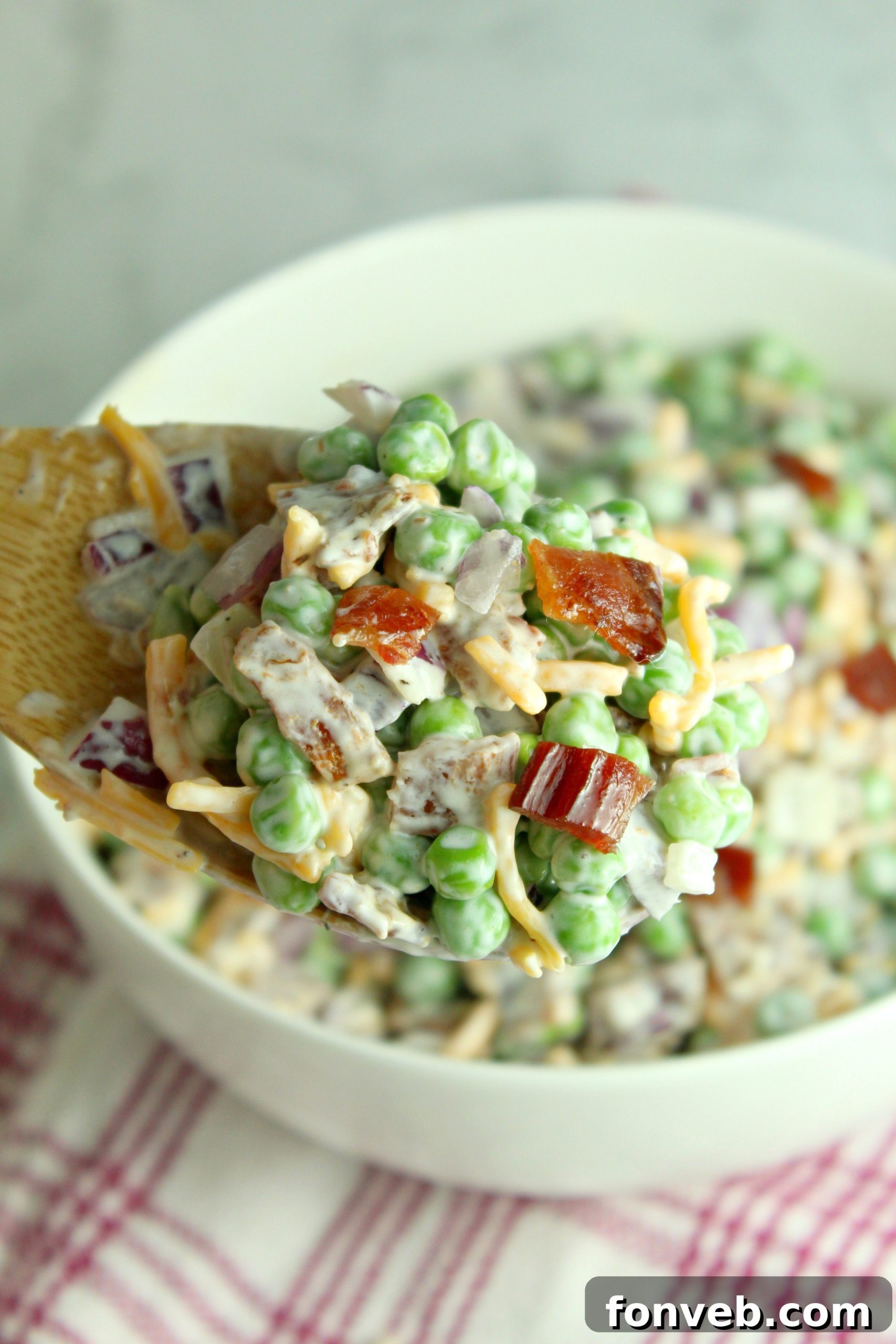 Smoky Bacon and Sweet Pea Salad 8 A spoon scooping a generous portion of Creamy Bacon Pea Salad, ready to be enjoyed.