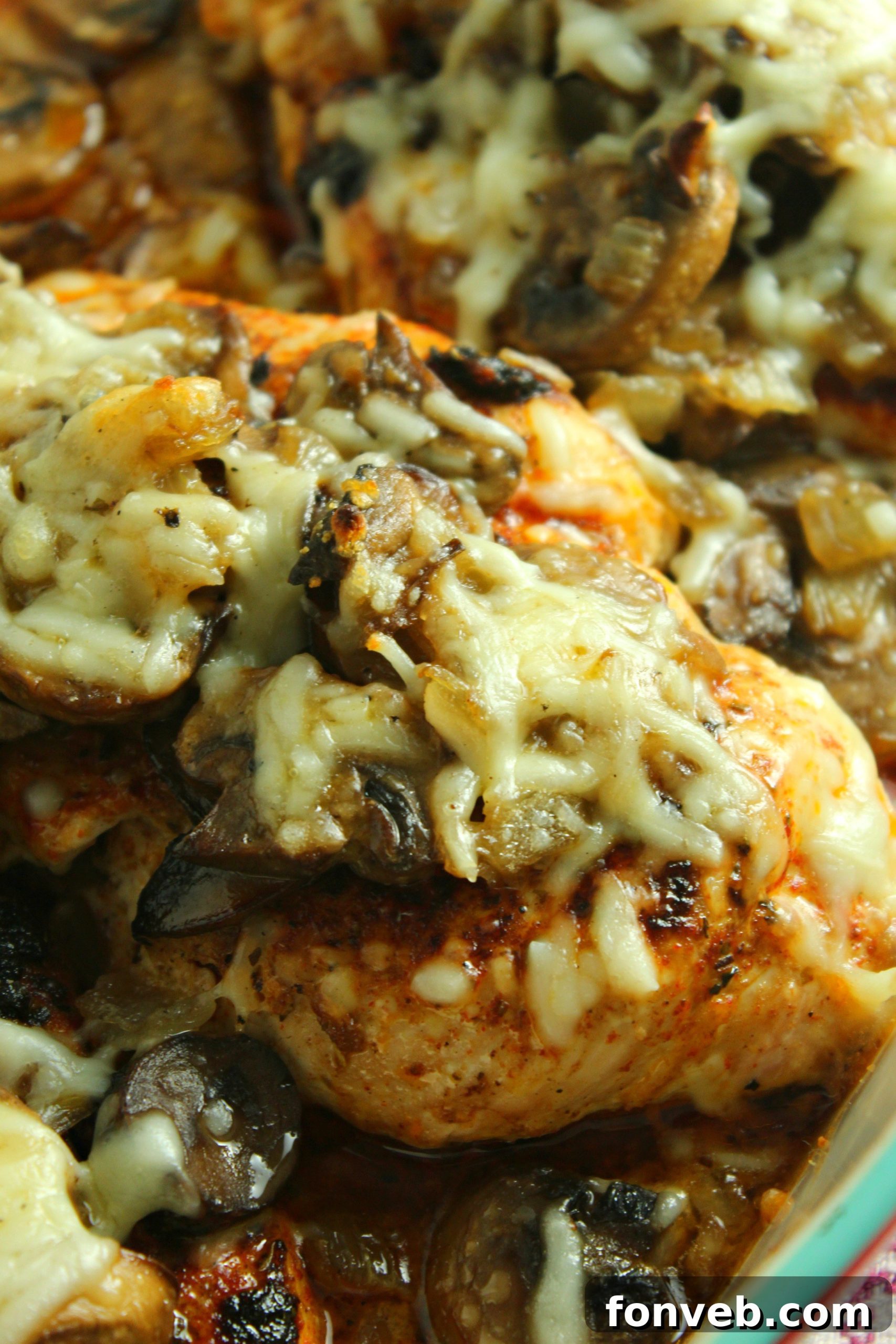 Creamy Cheesy Mushroom Chicken Keto Bake 3 A serving of baked chicken breast topped with caramelized onions, mushrooms, and melted cheese, ready to be enjoyed.