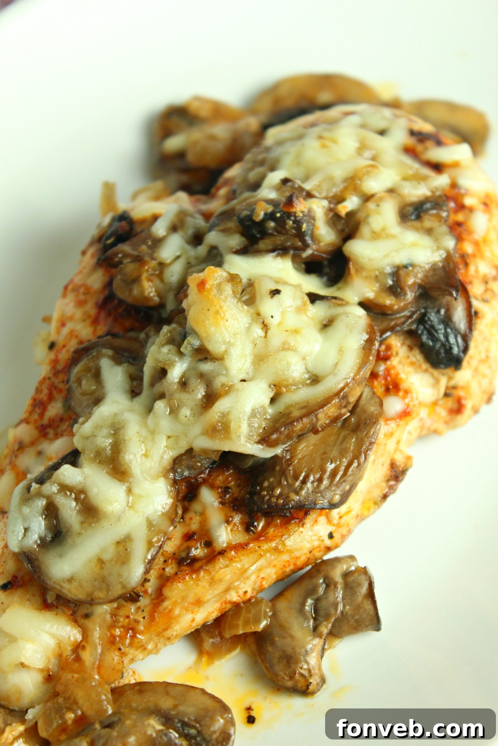 Creamy Cheesy Mushroom Chicken Keto Bake 6 Cooked chicken breasts topped with caramelized onions and mushrooms, with shredded mozzarella cheese sprinkled on top.