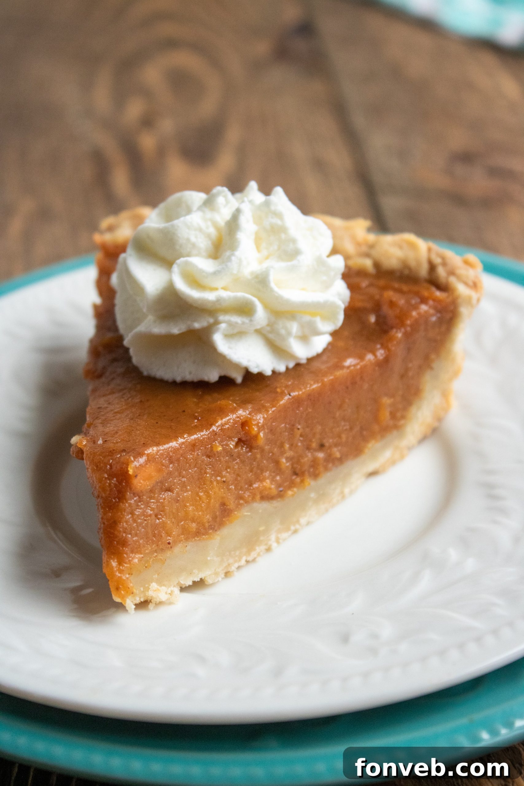 A sweet potato pie topped with whipped cream, garnished with cinnamon stick