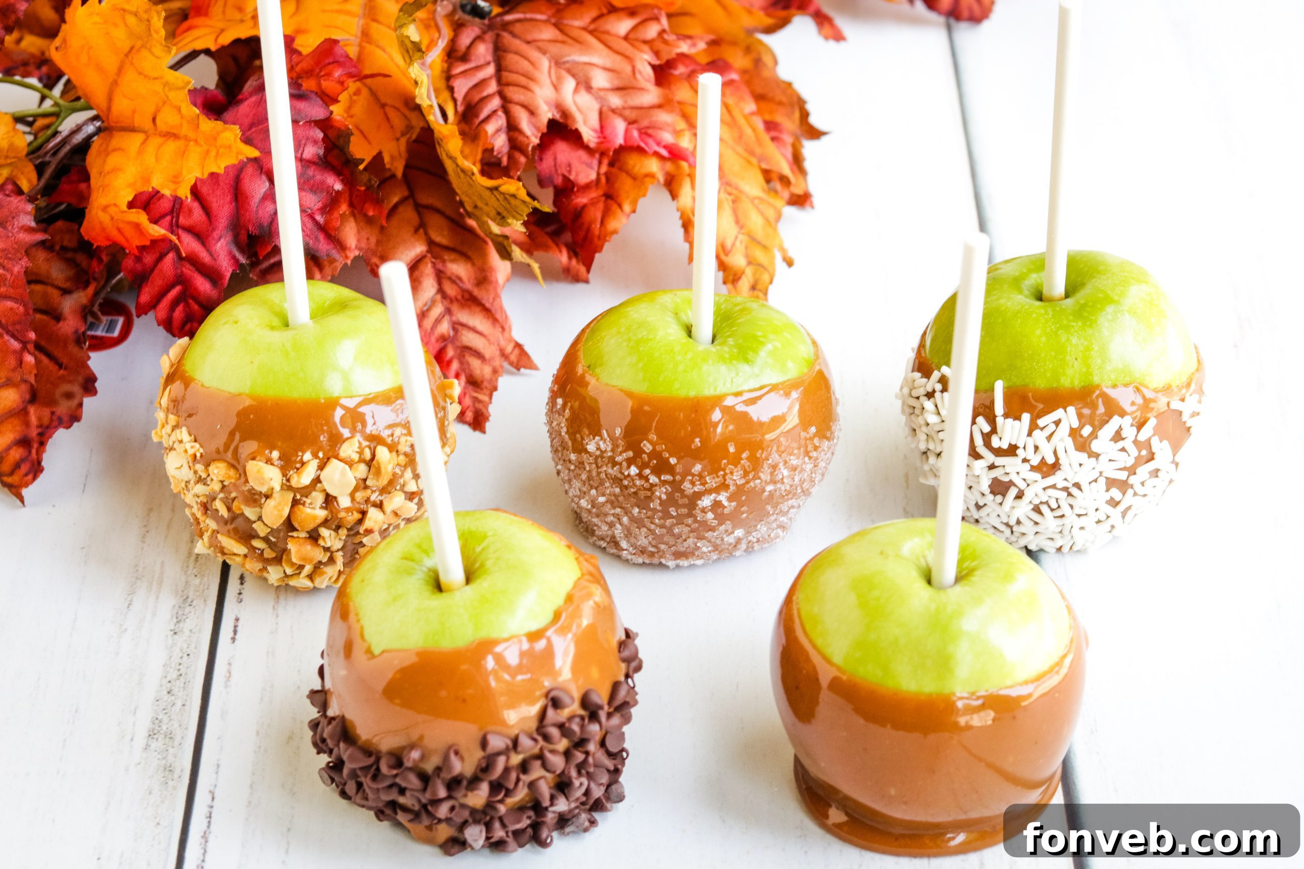 Hand dipping an apple into a pot of rich homemade caramel.