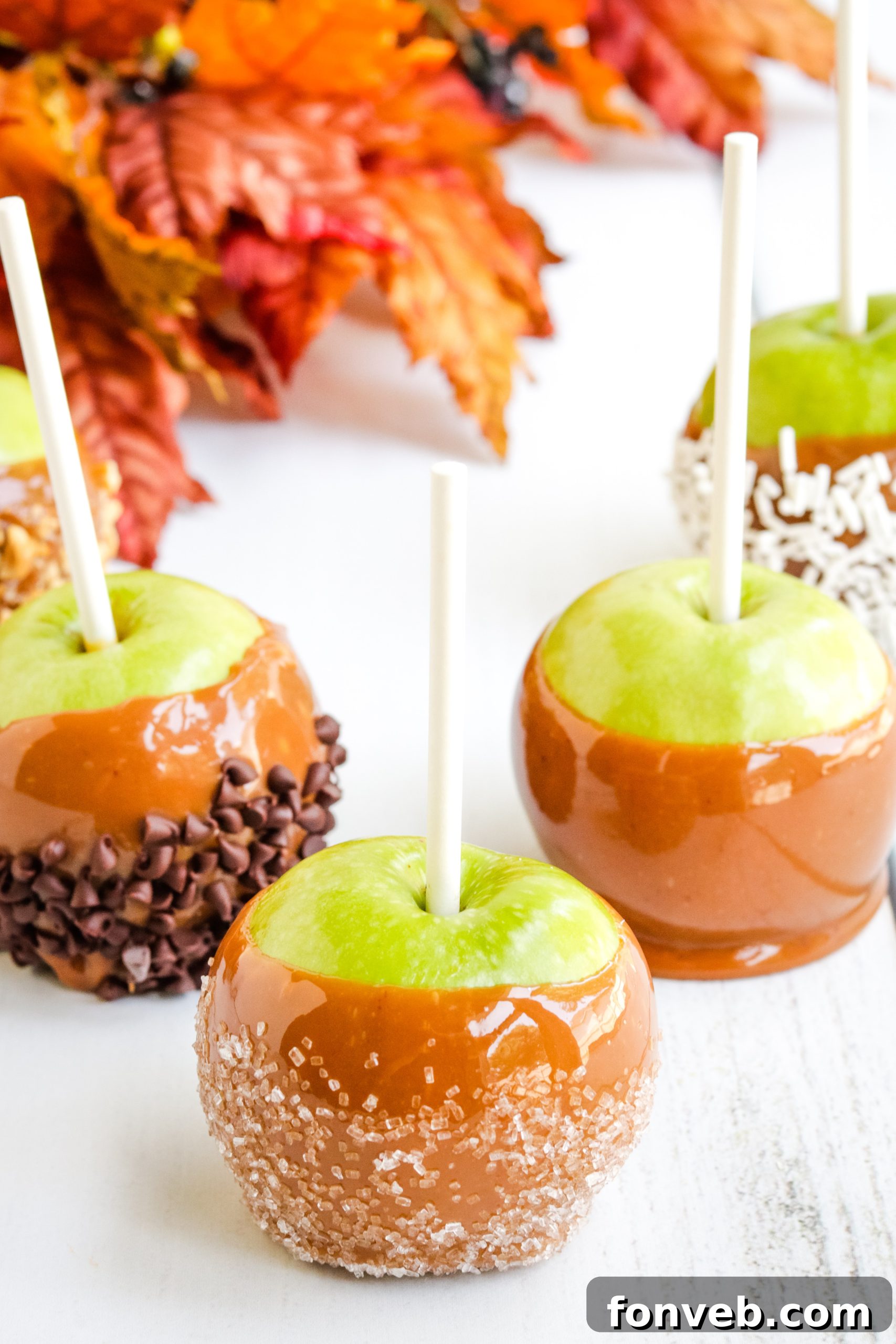 Caramel-covered apples cooling on parchment paper.