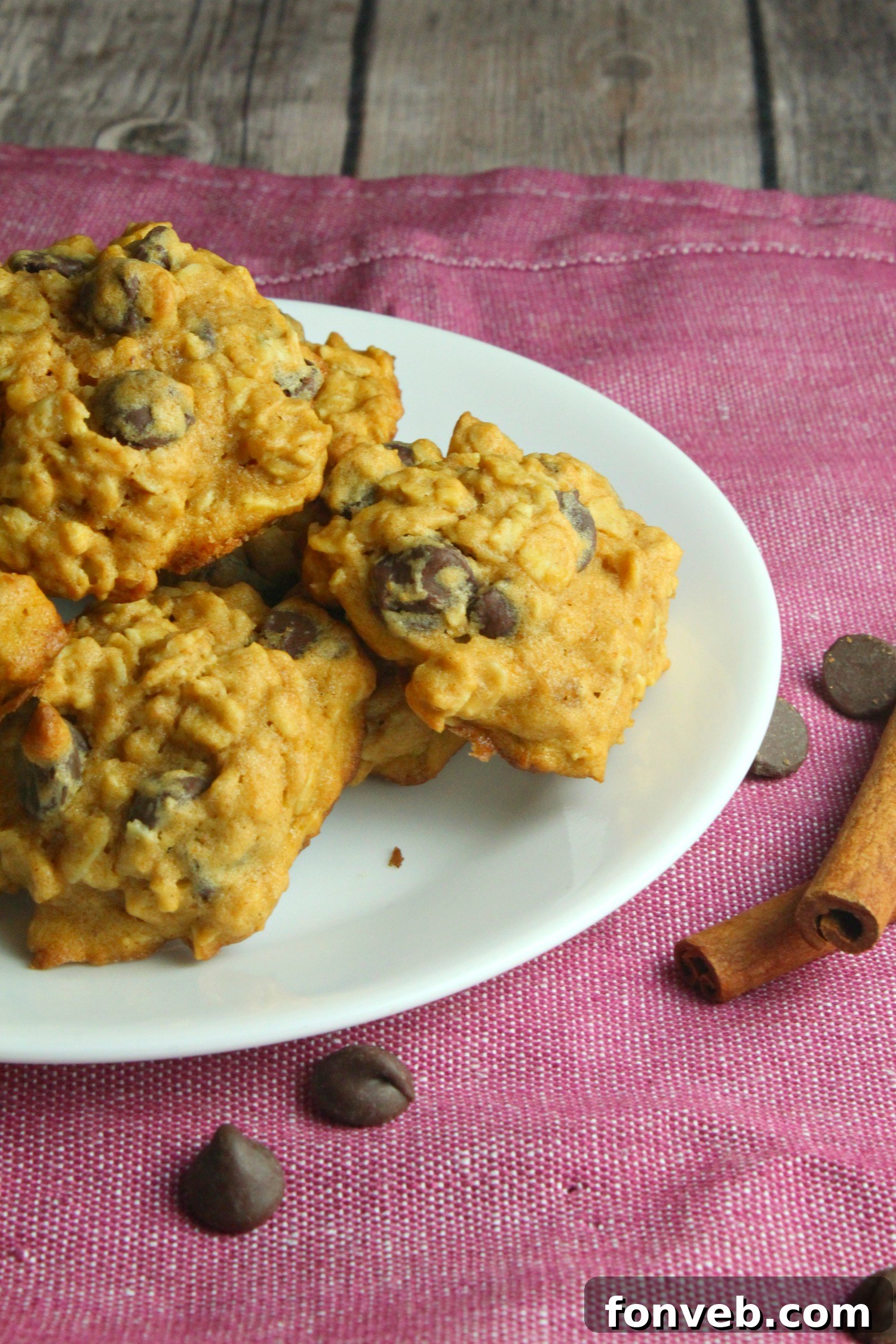 A single pumpkin oatmeal chocolate chip cookie placed on a wooden surface, highlighting its homemade charm