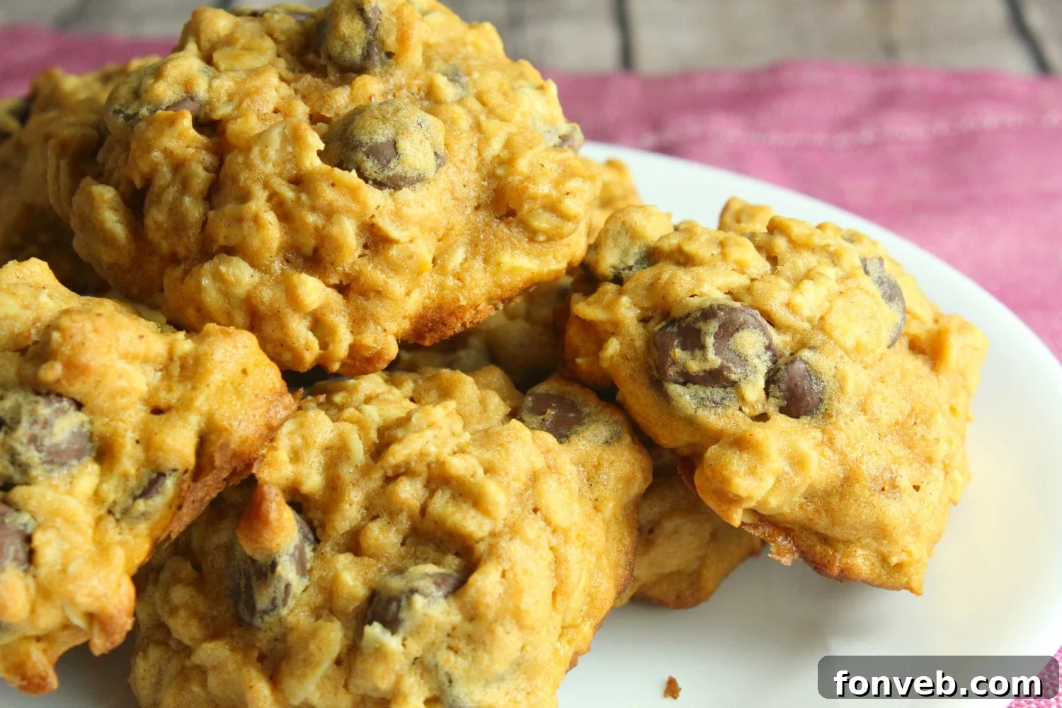 Close-up of a pumpkin oatmeal chocolate chip cookie with a bite taken out, showing its moist interior and melting chocolate