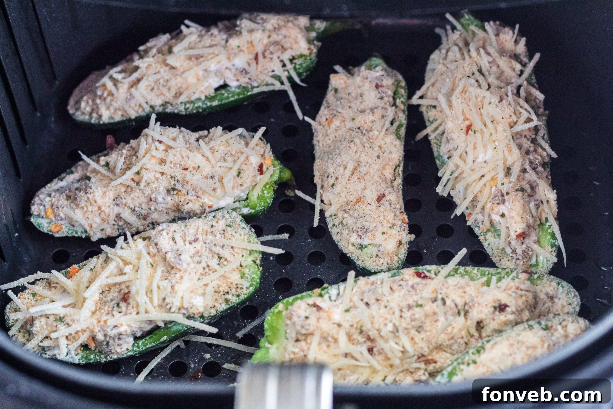 Hands filling jalapeno halves with cheese and sausage mixture