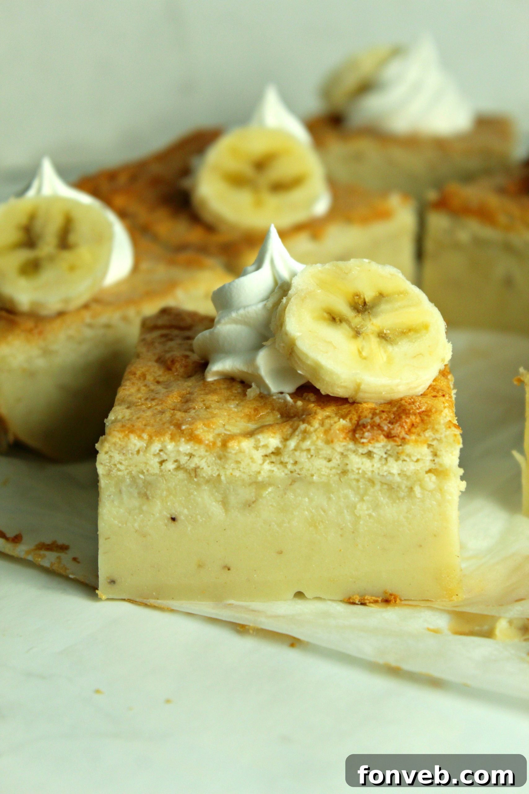 Banana Alchemy Cake 9 Close-up side view of a perfect slice of Banana Magic Cake on parchment paper, showing all three layers clearly.