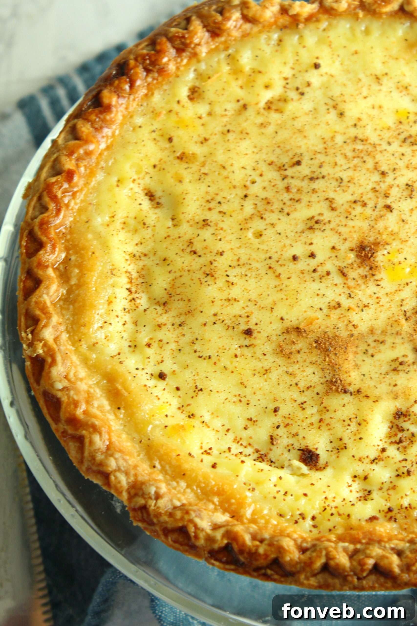 A slice of creamy custard pie on a plate, garnished with a sprinkle of nutmeg, ready to be enjoyed.