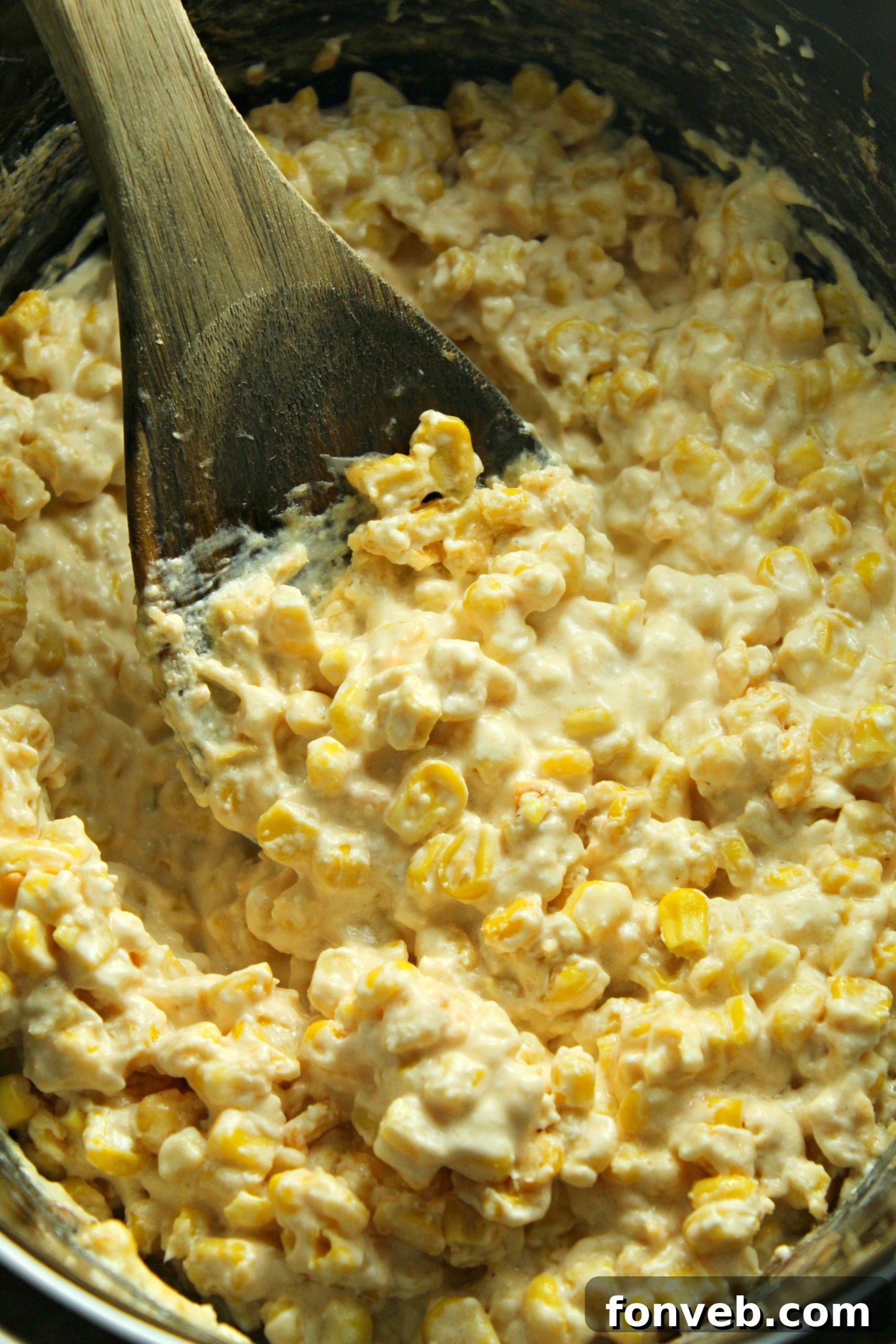 A large bowl of creamy slow cooker cheesy corn, garnished with fresh herbs, showcasing its rich texture.