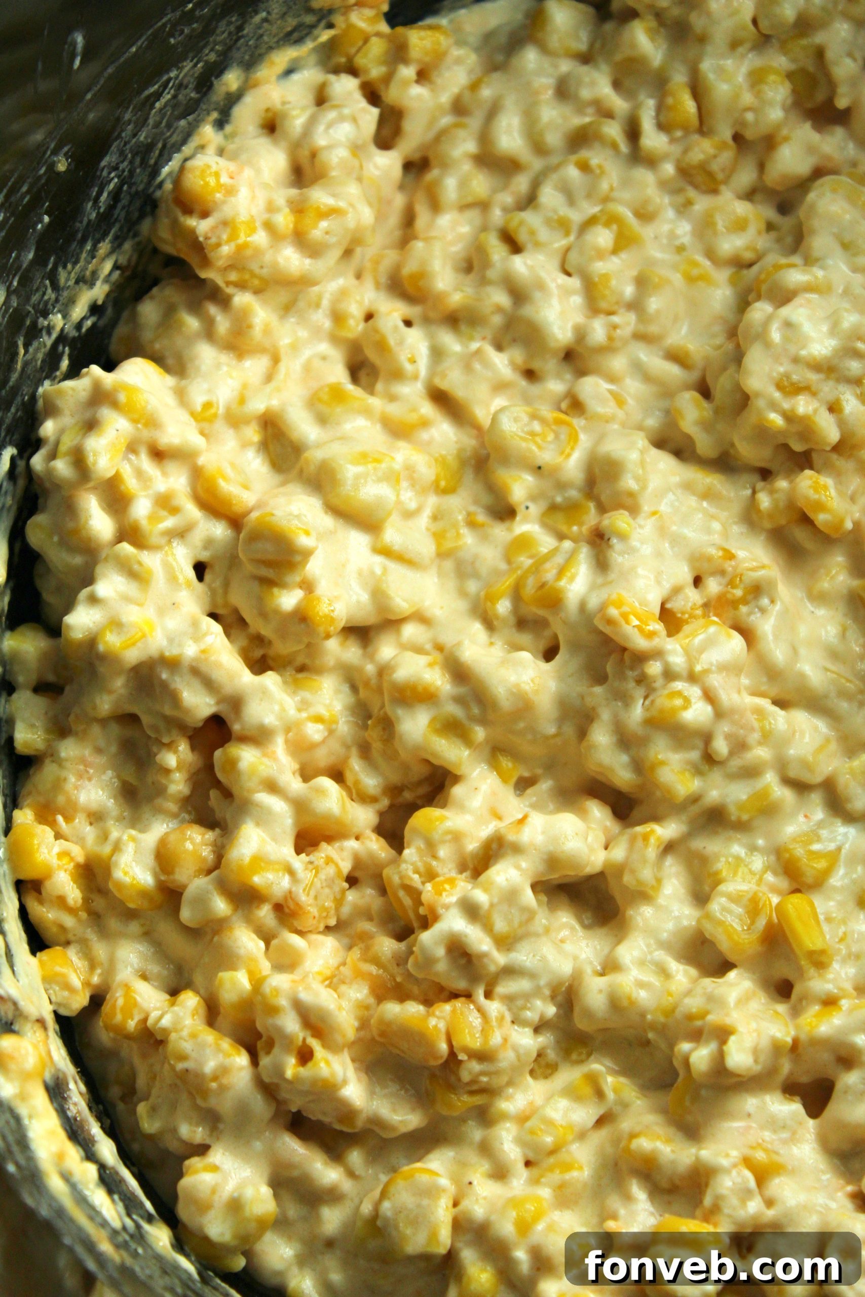 Overhead shot of slow cooker creamy cheesy corn, showing the vibrant yellow corn and creamy sauce.