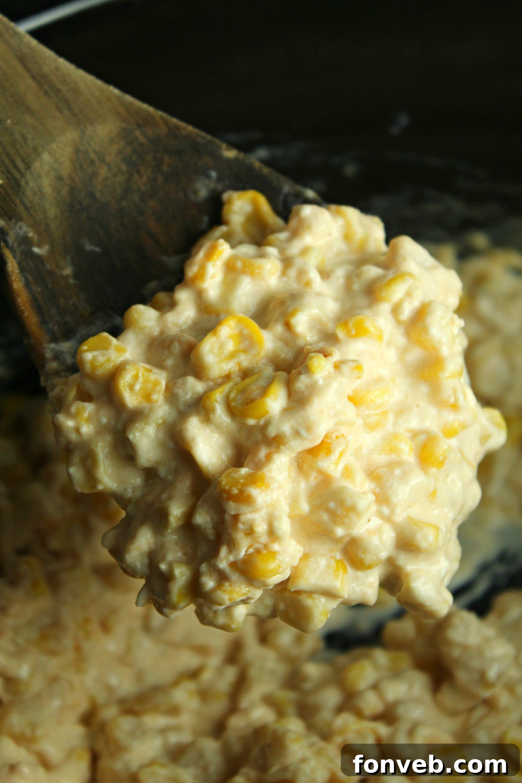 Close-up of the finished creamy slow cooker cheesy corn, showing individual kernels coated in cheese sauce.