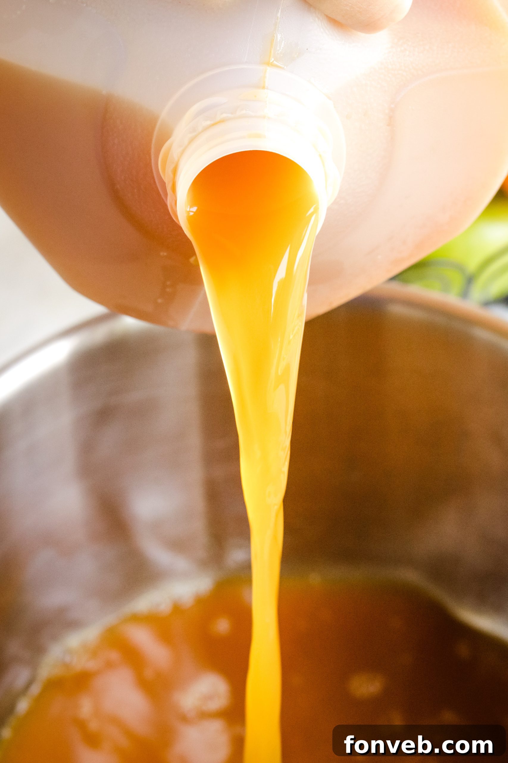 Cozy Slow Cooker Spiced Cider 3 A close-up of hot mulled cider in a pot, with visible apple and orange slices and cinnamon sticks.