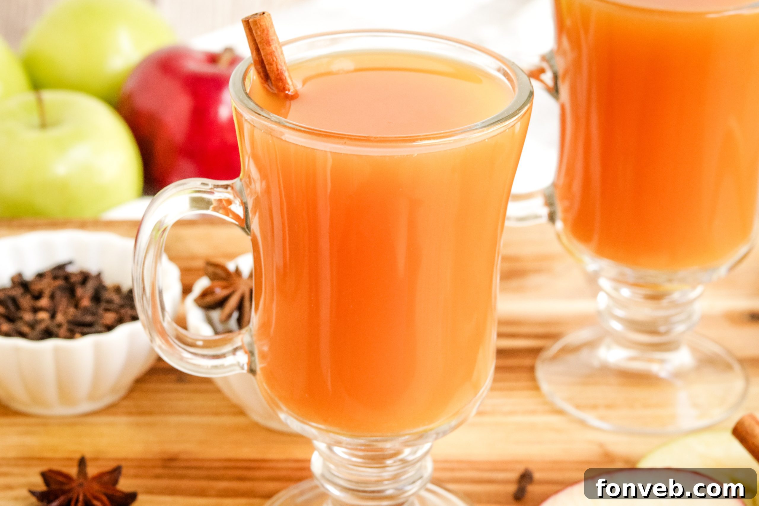Cozy Slow Cooker Spiced Cider 10 A large pot of mulled cider being stirred, with various ingredients like fruit and spices visible in the liquid.