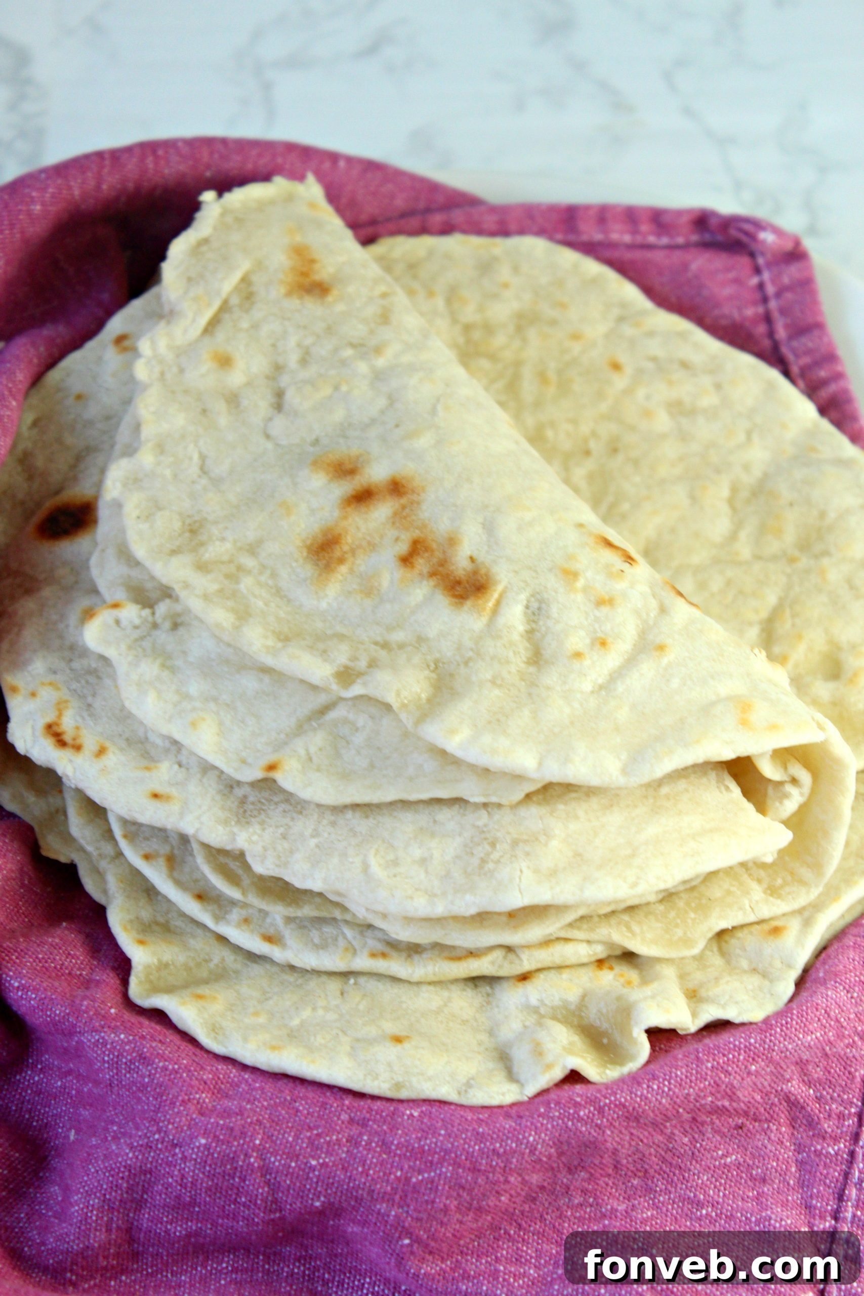 Flattened dough balls resting under a towel